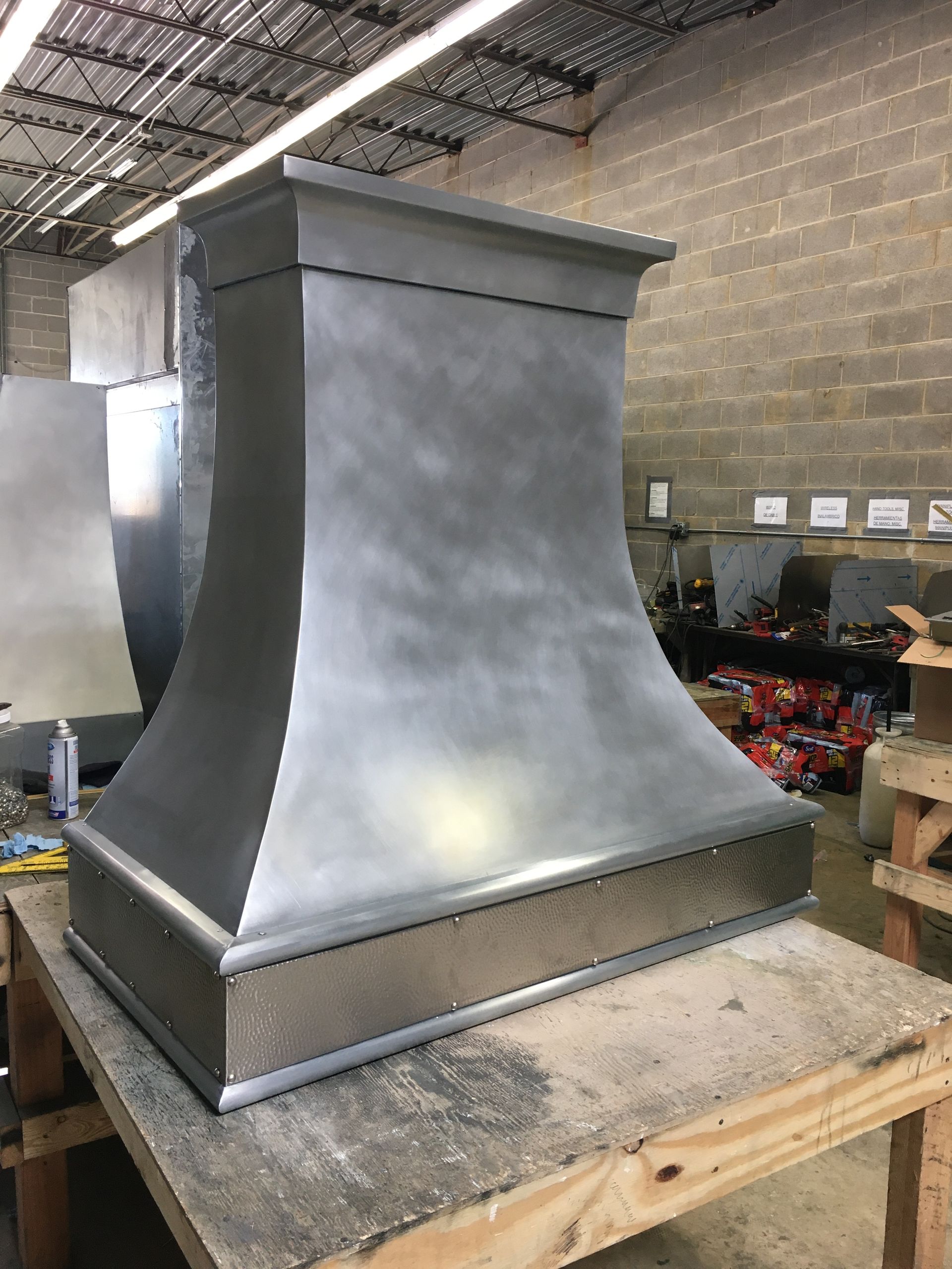 A stainless steel hood is sitting on top of a wooden table.