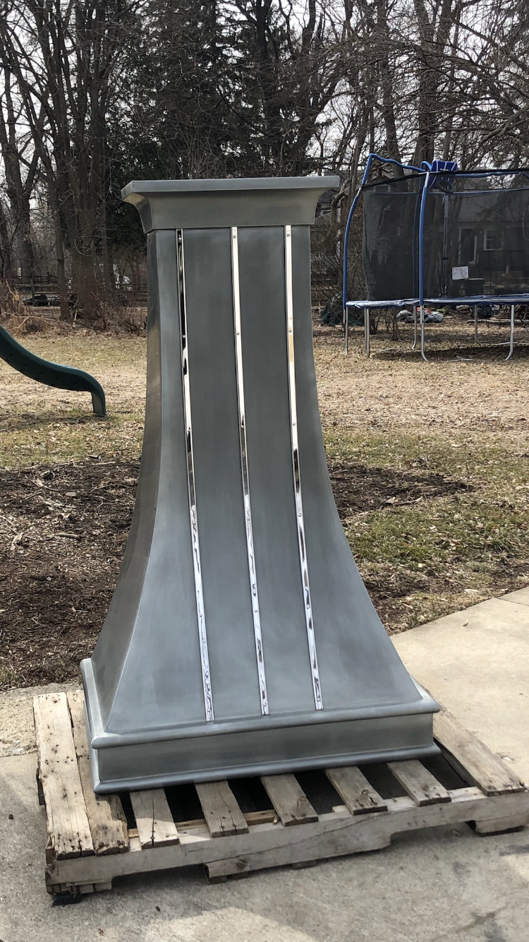 A stainless steel chimney is sitting on top of a wooden pallet.