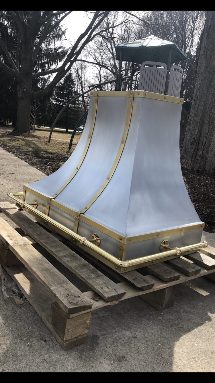 A metal hood is sitting on top of a wooden pallet.