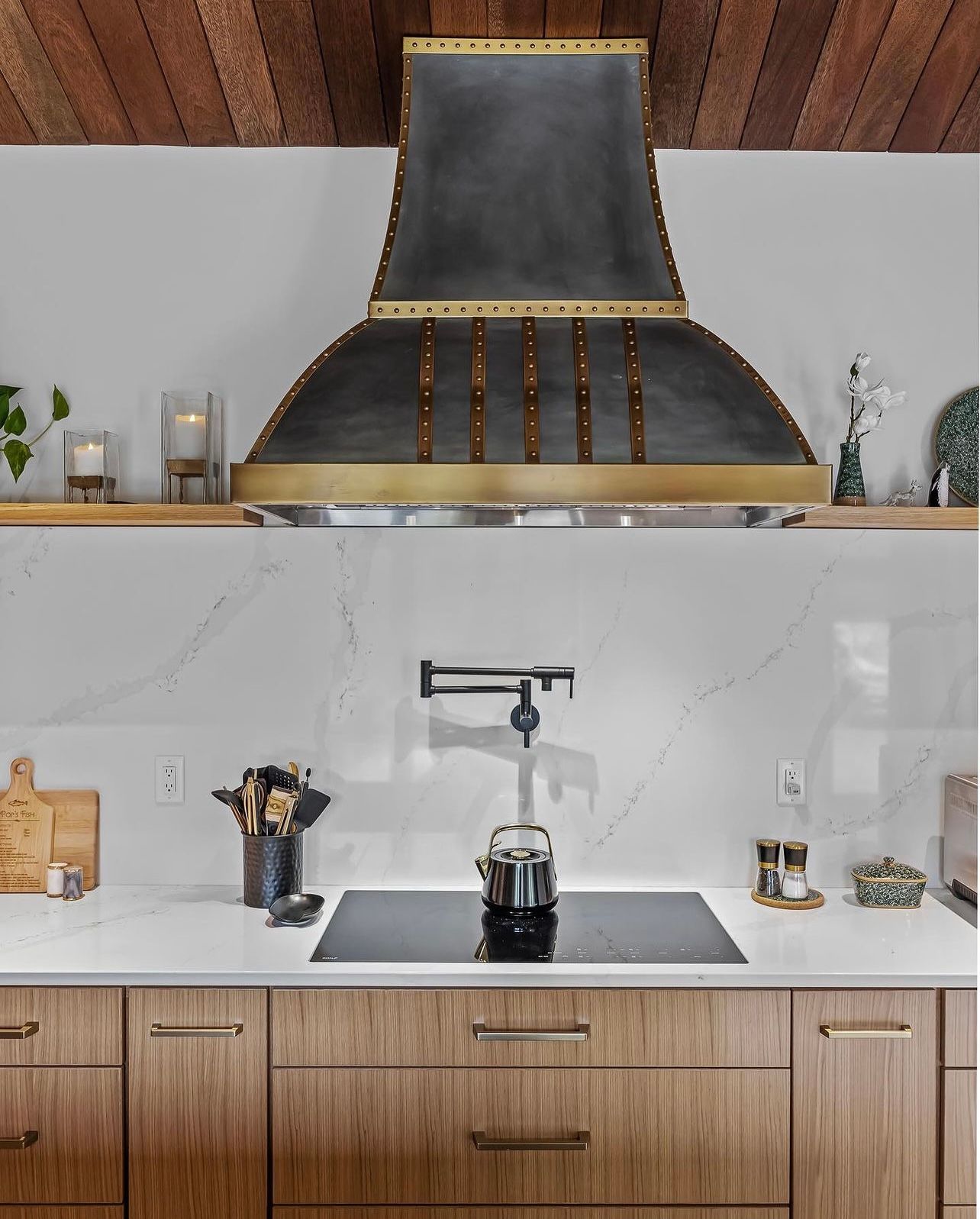 A kitchen with a stove top oven and a hood above it