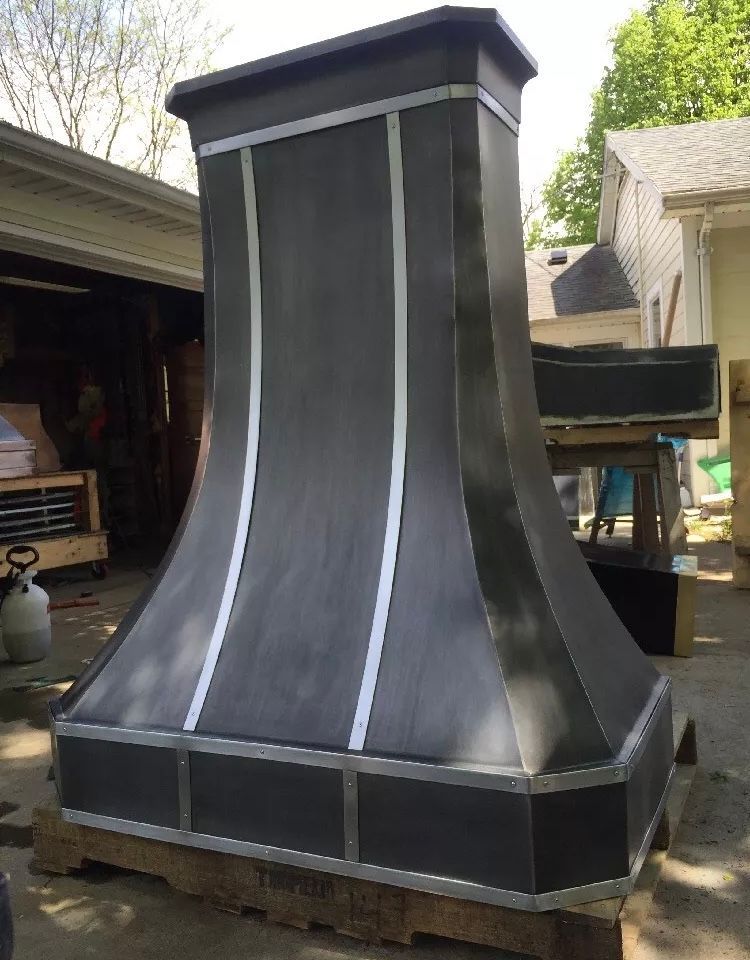 A black chimney is sitting on a wooden pallet in front of a house.