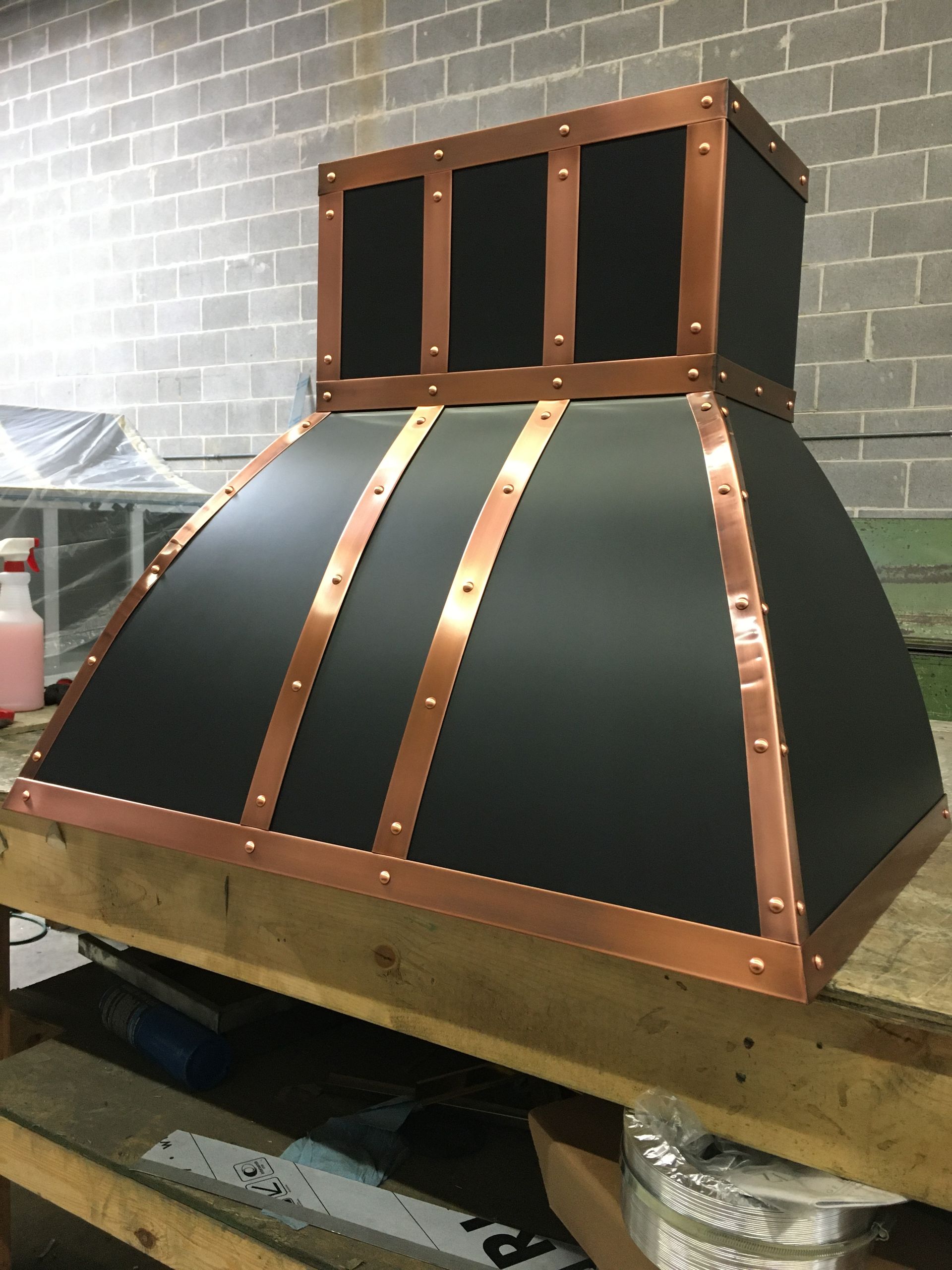 A black and copper hood is sitting on a wooden table.