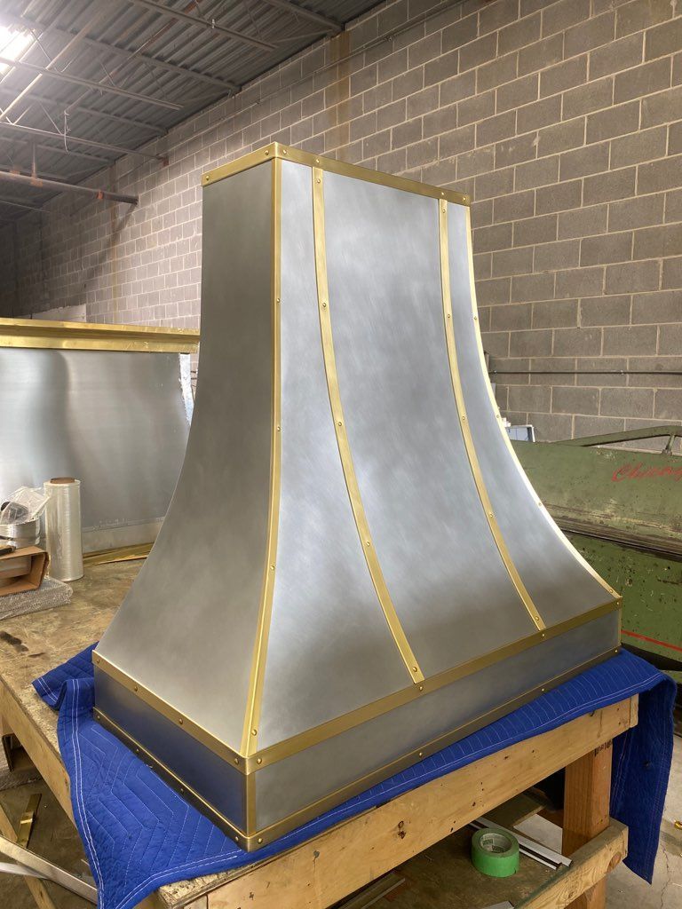 A stainless steel hood is sitting on top of a wooden table.