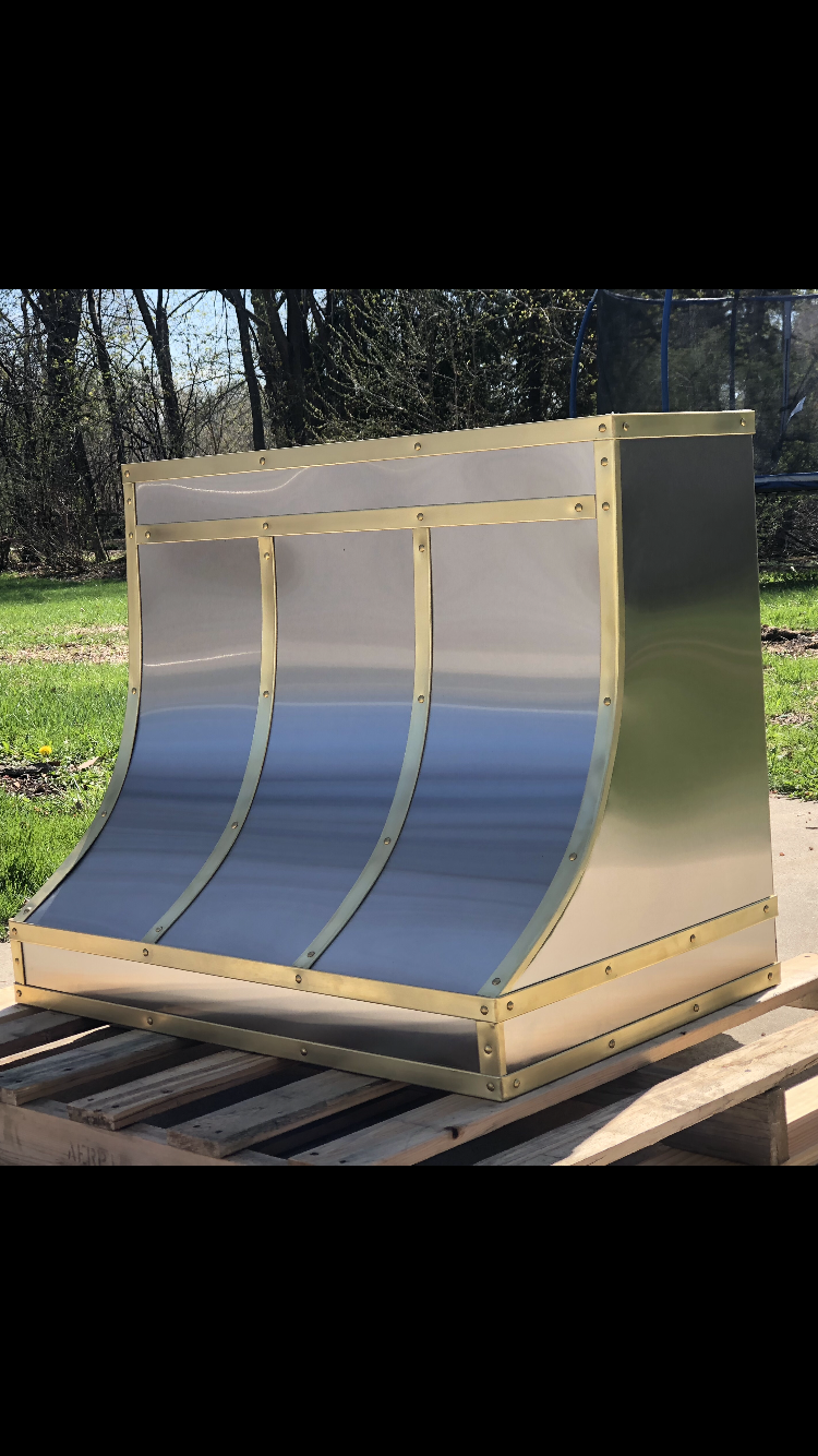 A stainless steel hood is sitting on top of a wooden pallet.