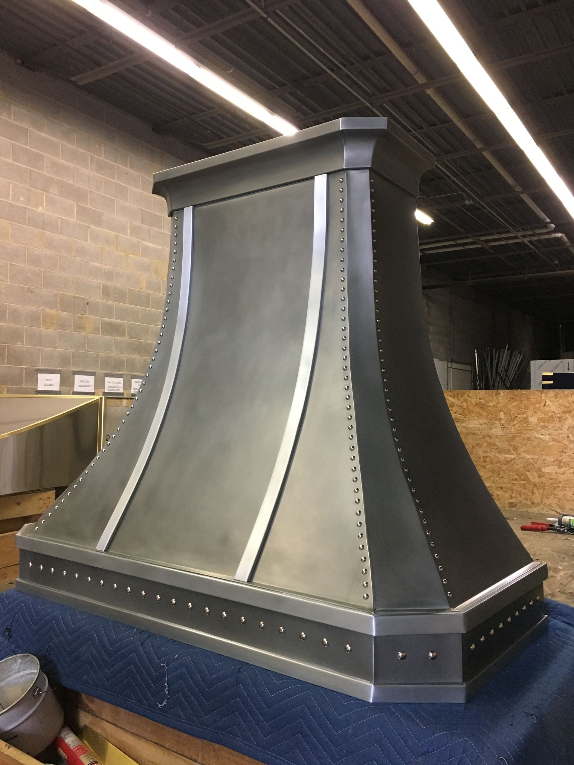A stainless steel hood is sitting on top of a blue table.