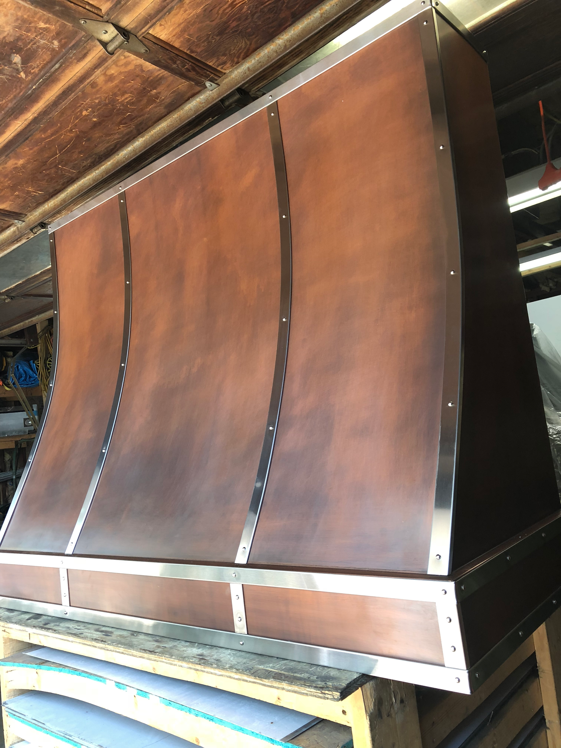 A copper hood is sitting on top of a wooden table.