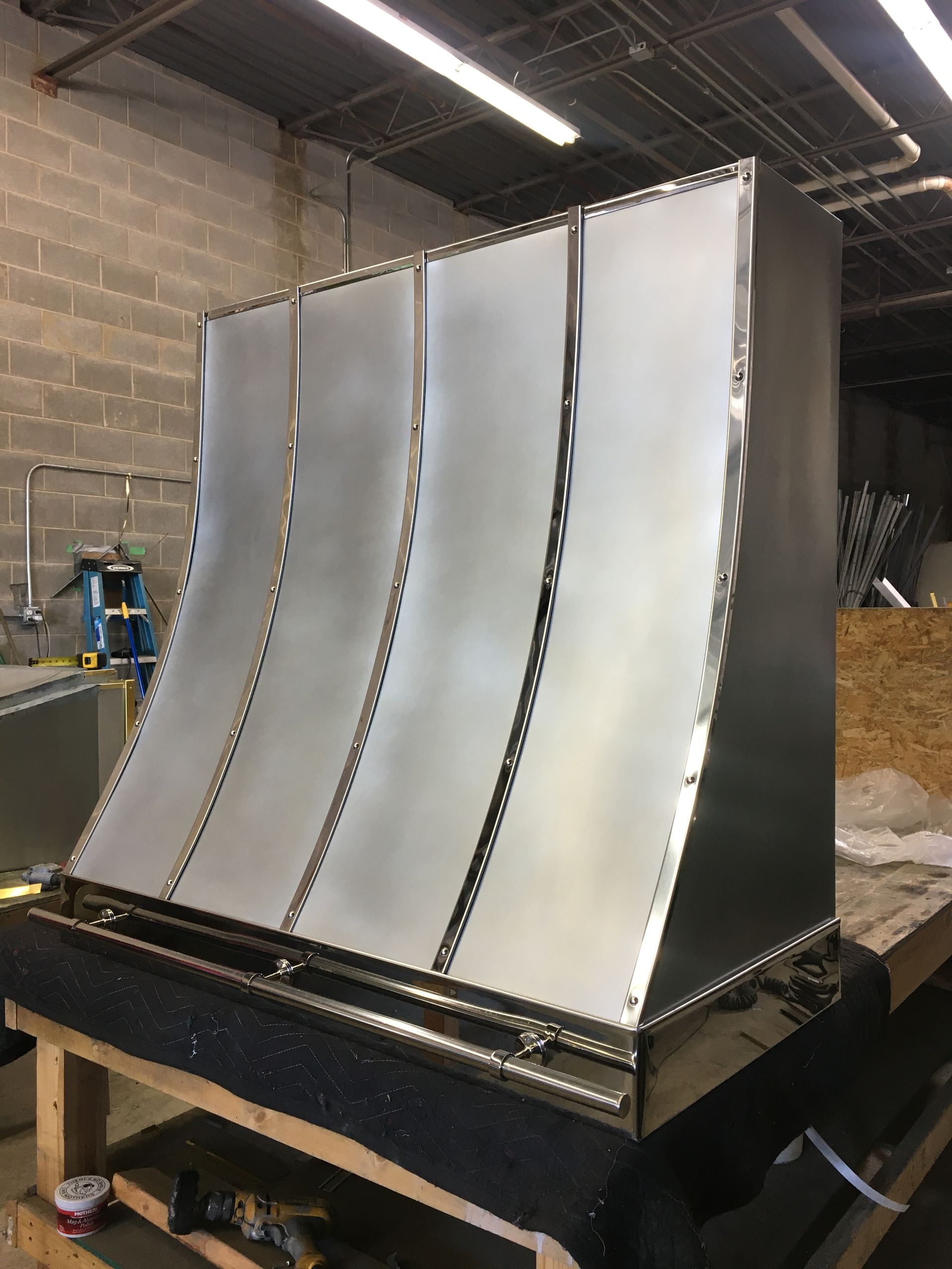 A stainless steel hood is sitting on top of a wooden table in a room.