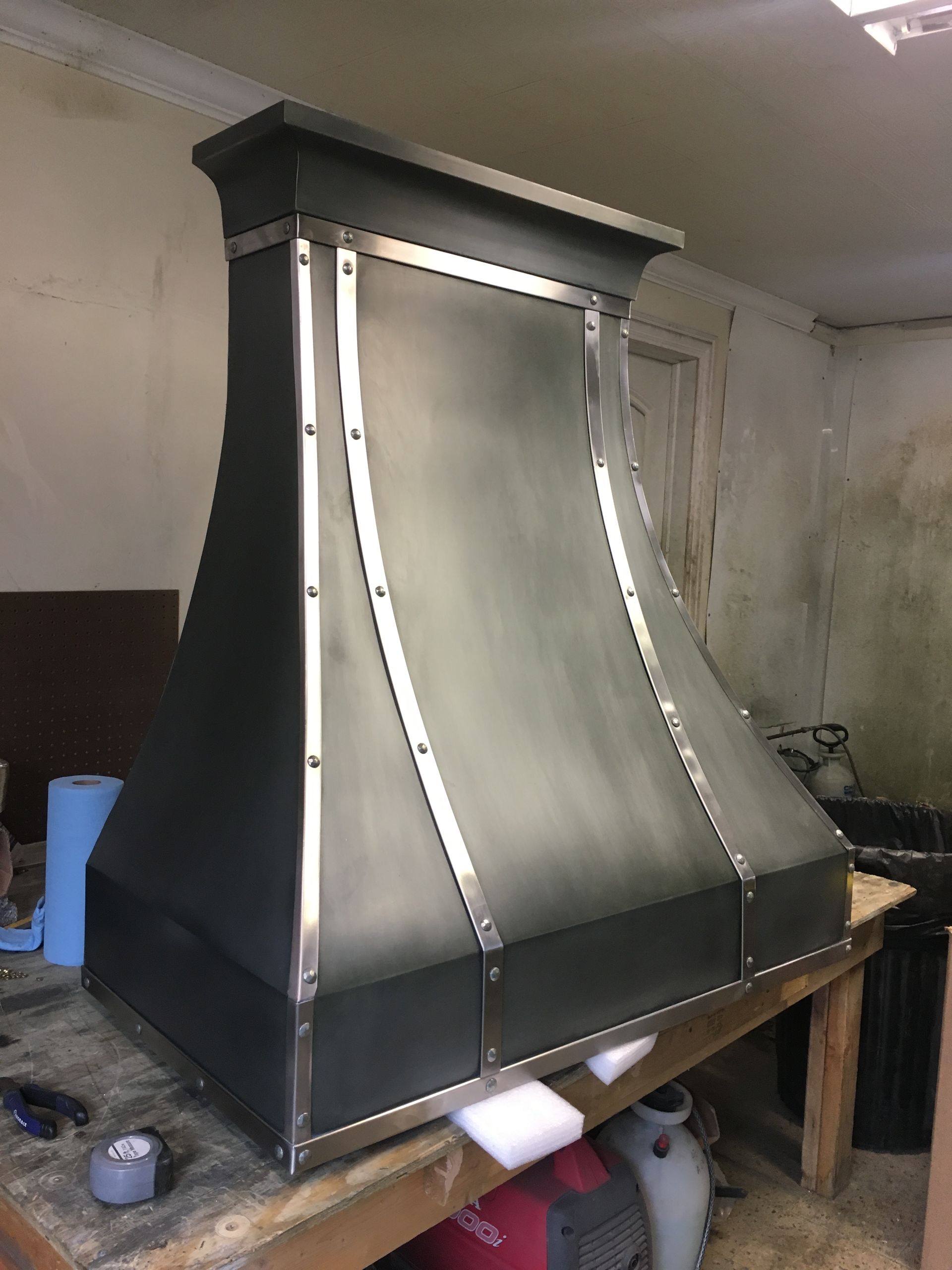 A metal hood is sitting on top of a wooden table.