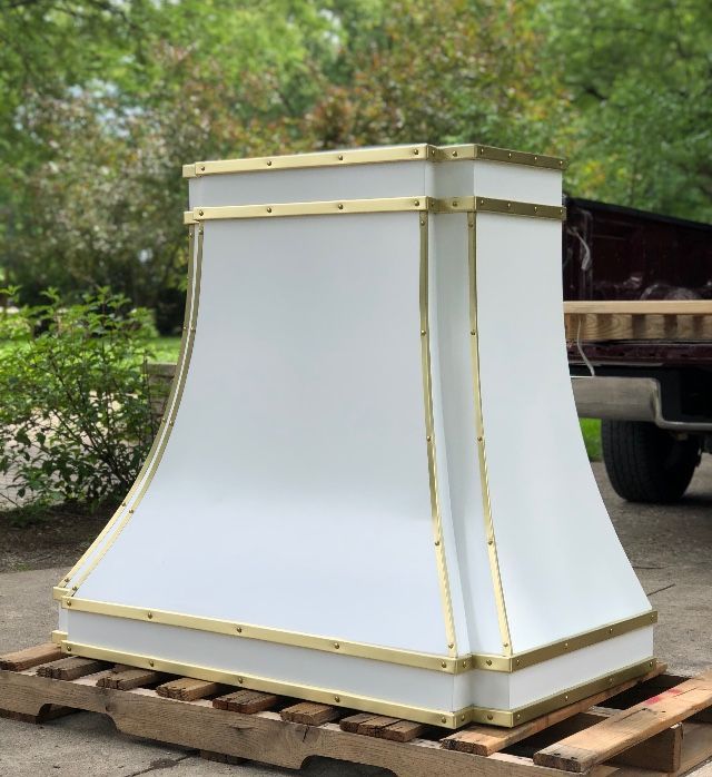 A white and gold hood is sitting on a wooden pallet.