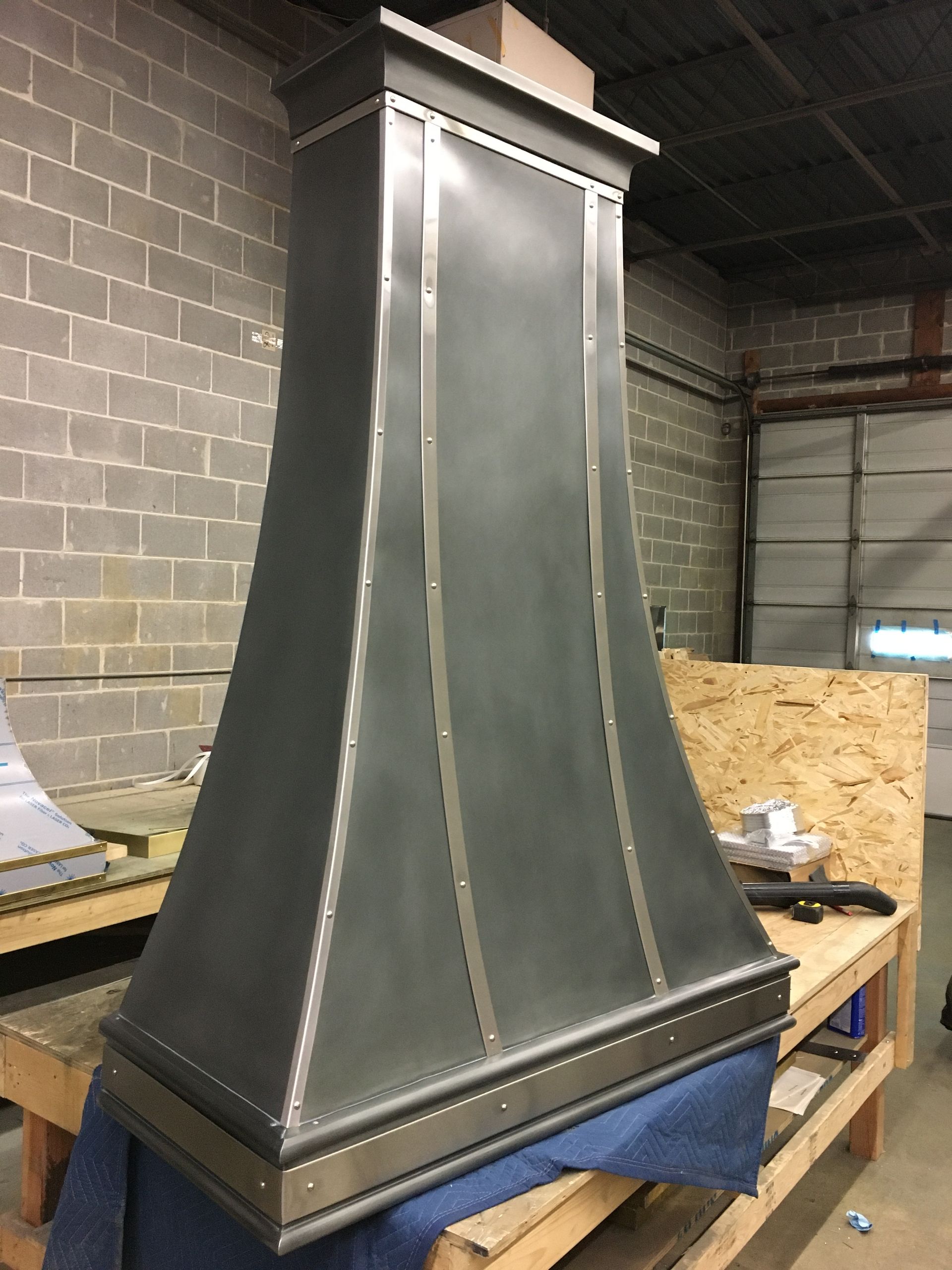 A stainless steel hood is sitting on top of a wooden table.