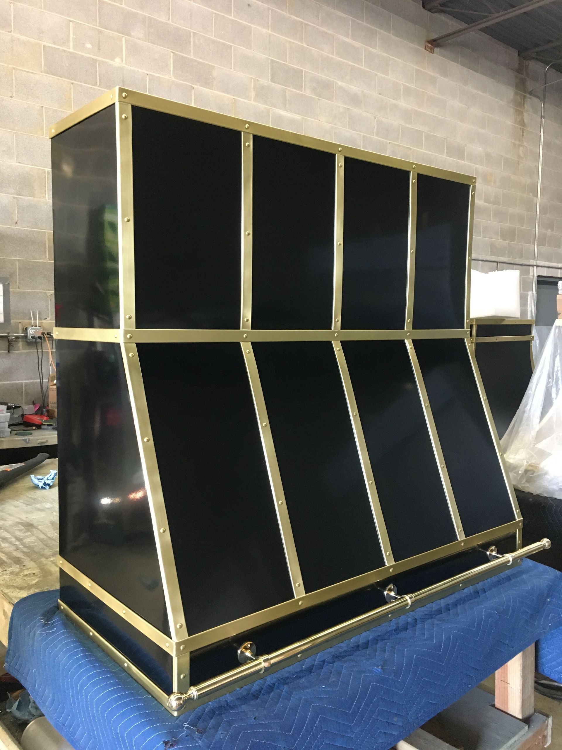 A black and gold cabinet is sitting on top of a blue table.