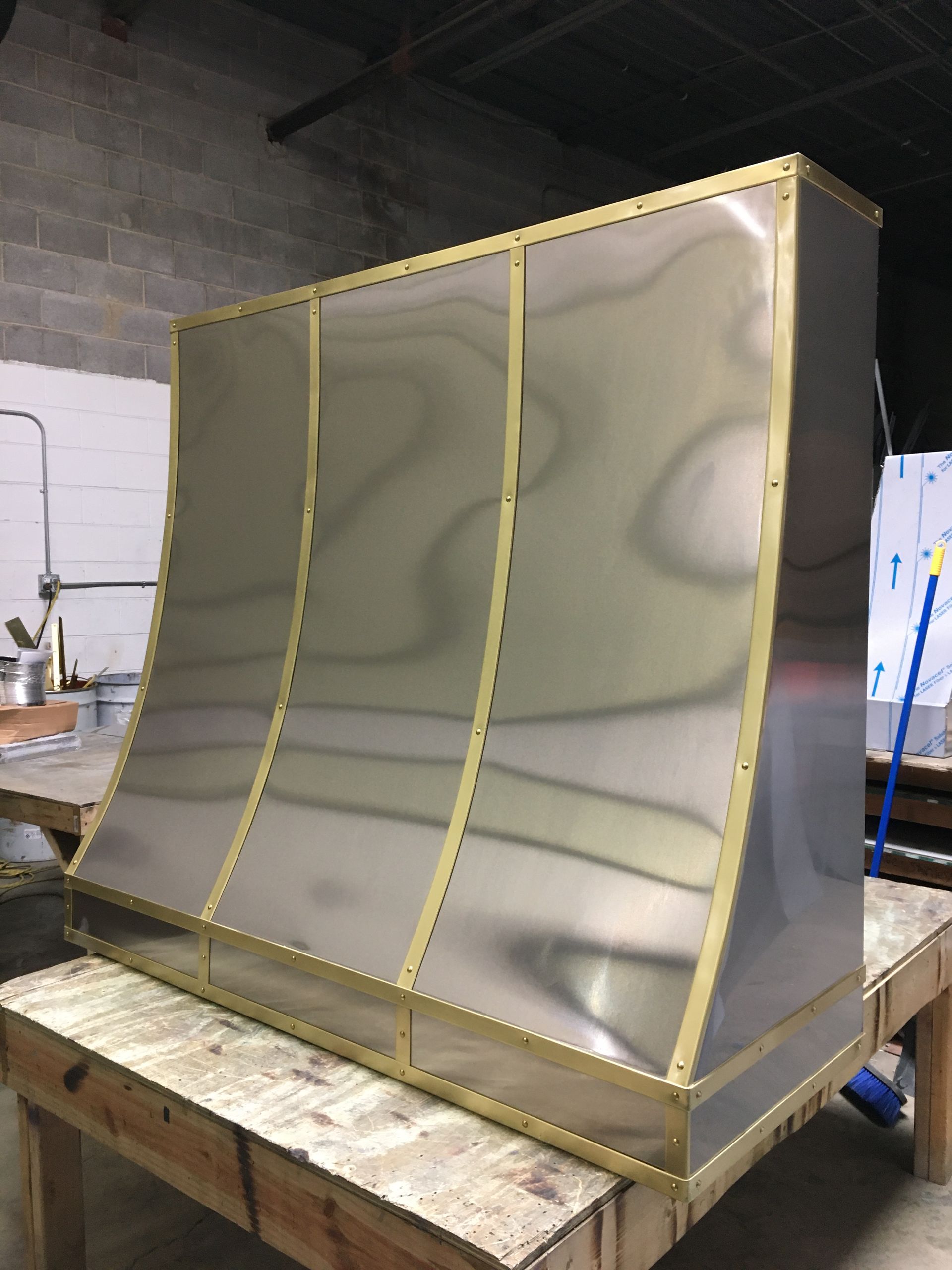 A stainless steel hood is sitting on top of a wooden table.