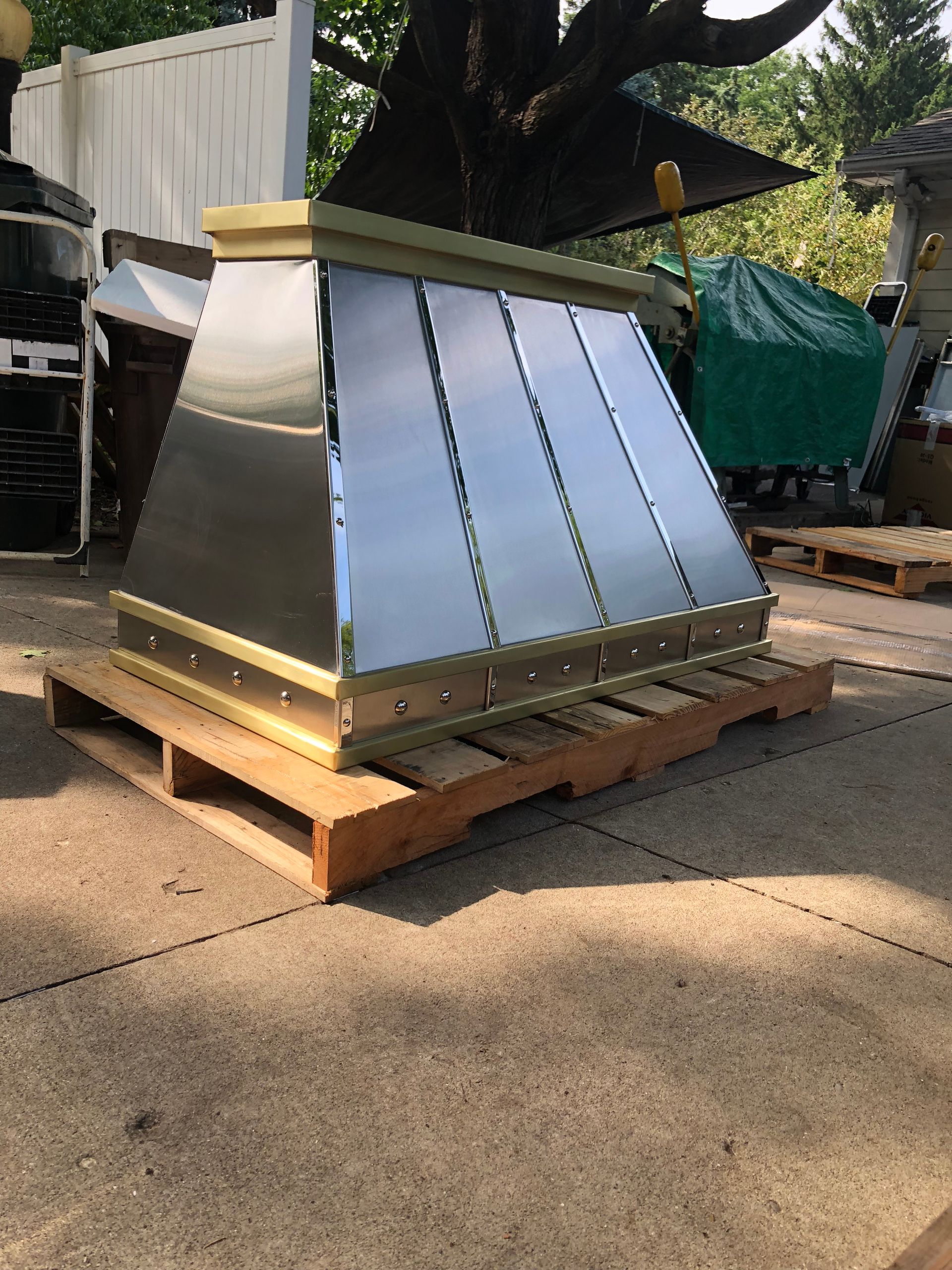 A stainless steel hood is sitting on top of a wooden pallet.