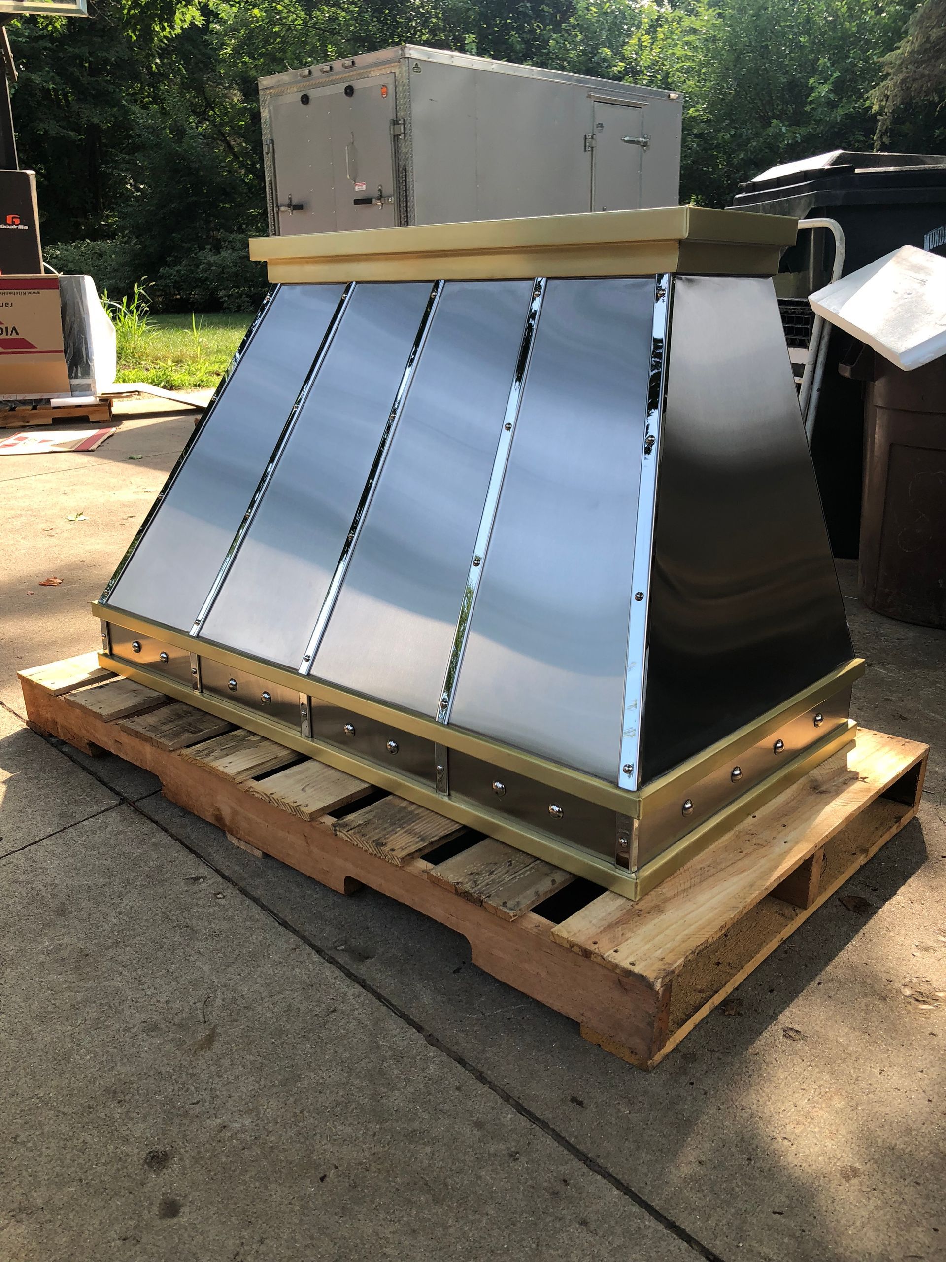 A stainless steel hood is sitting on top of a wooden pallet.