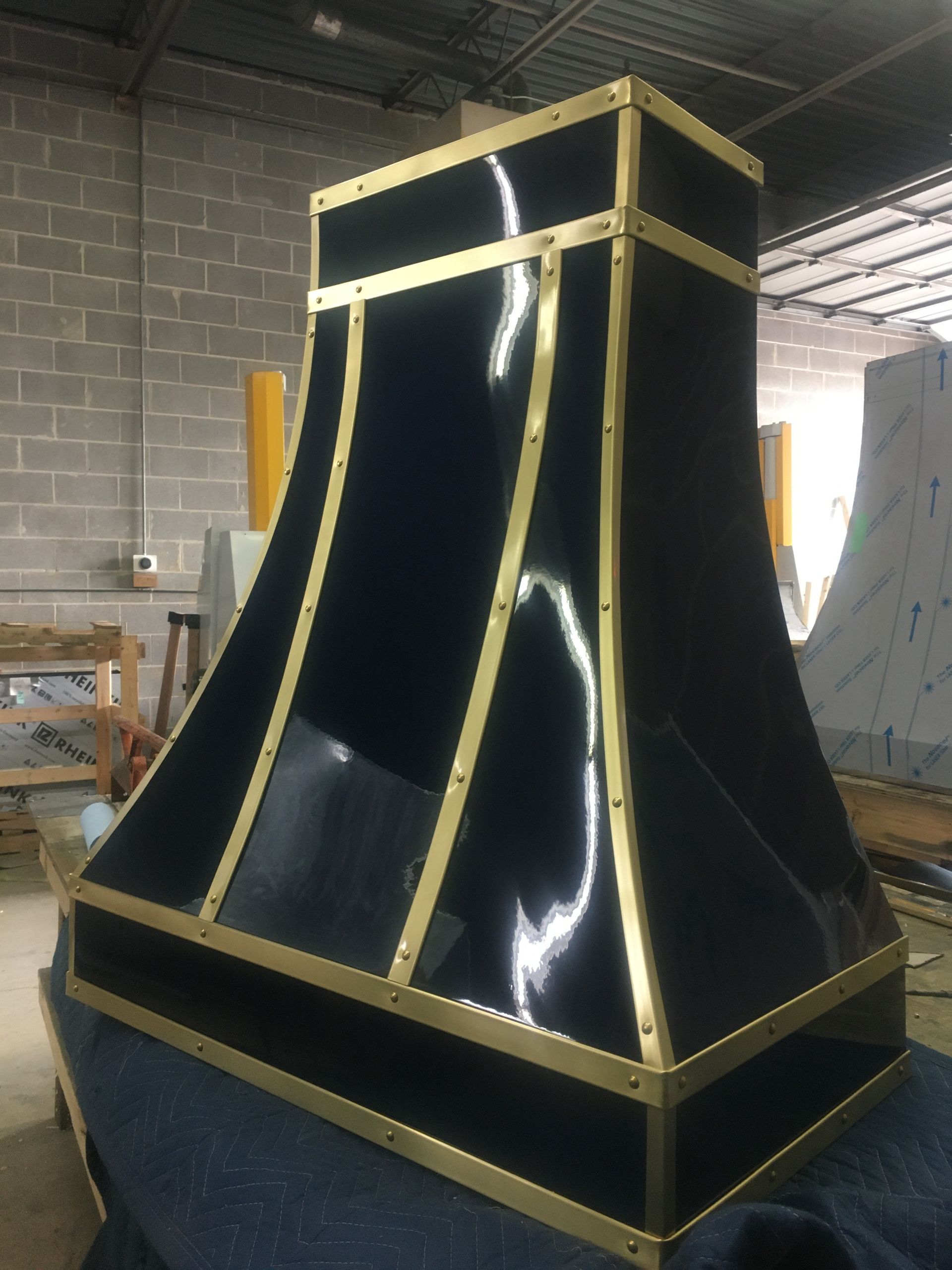 A black and gold hood is sitting on a table in a warehouse.