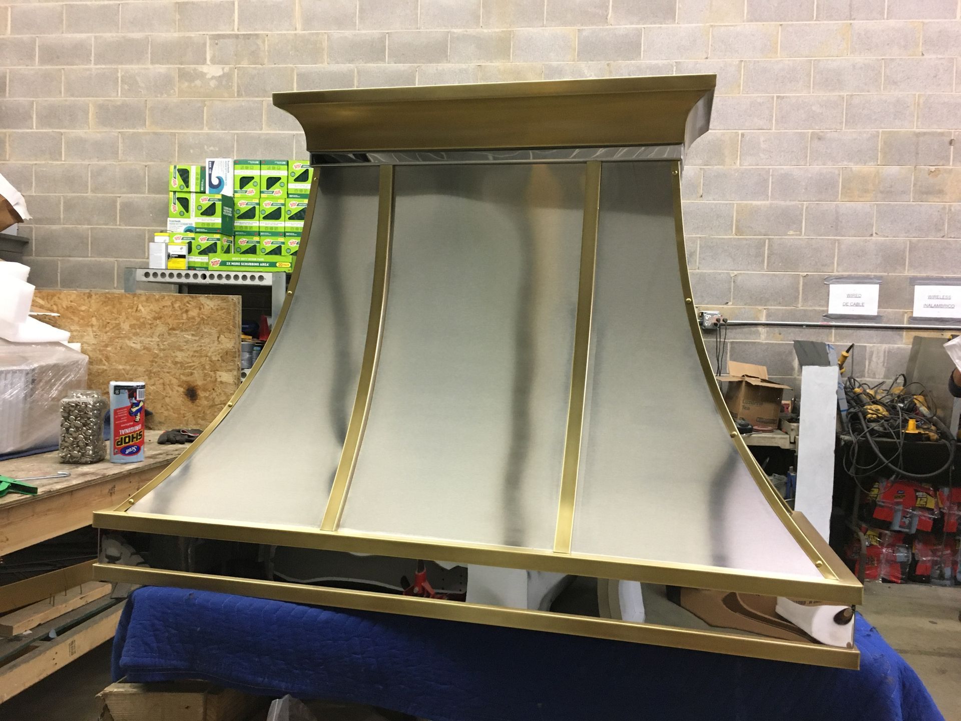 A brass and stainless steel hood is sitting on top of a blue table.