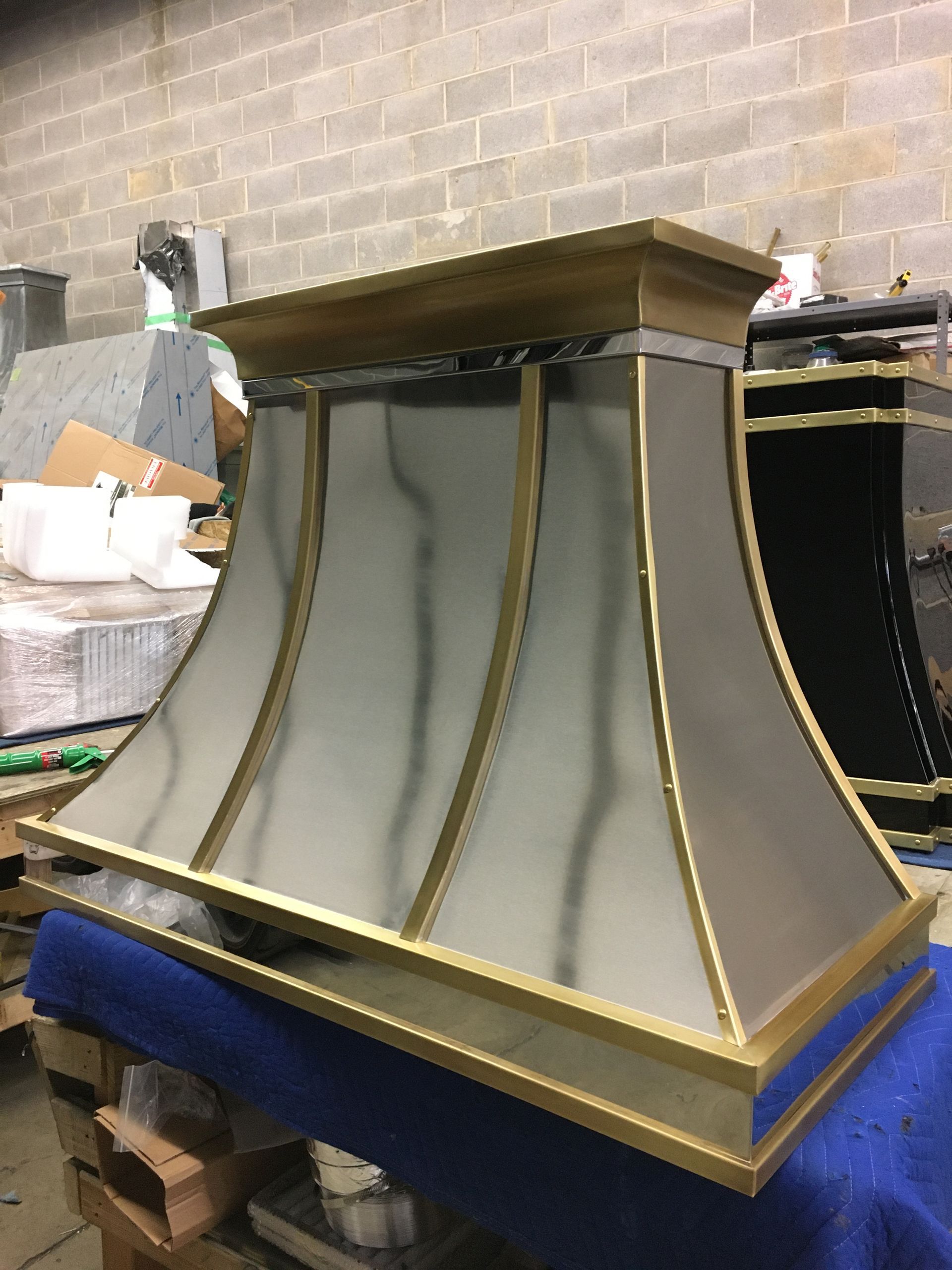 A brass and stainless steel hood is sitting on a blue table.