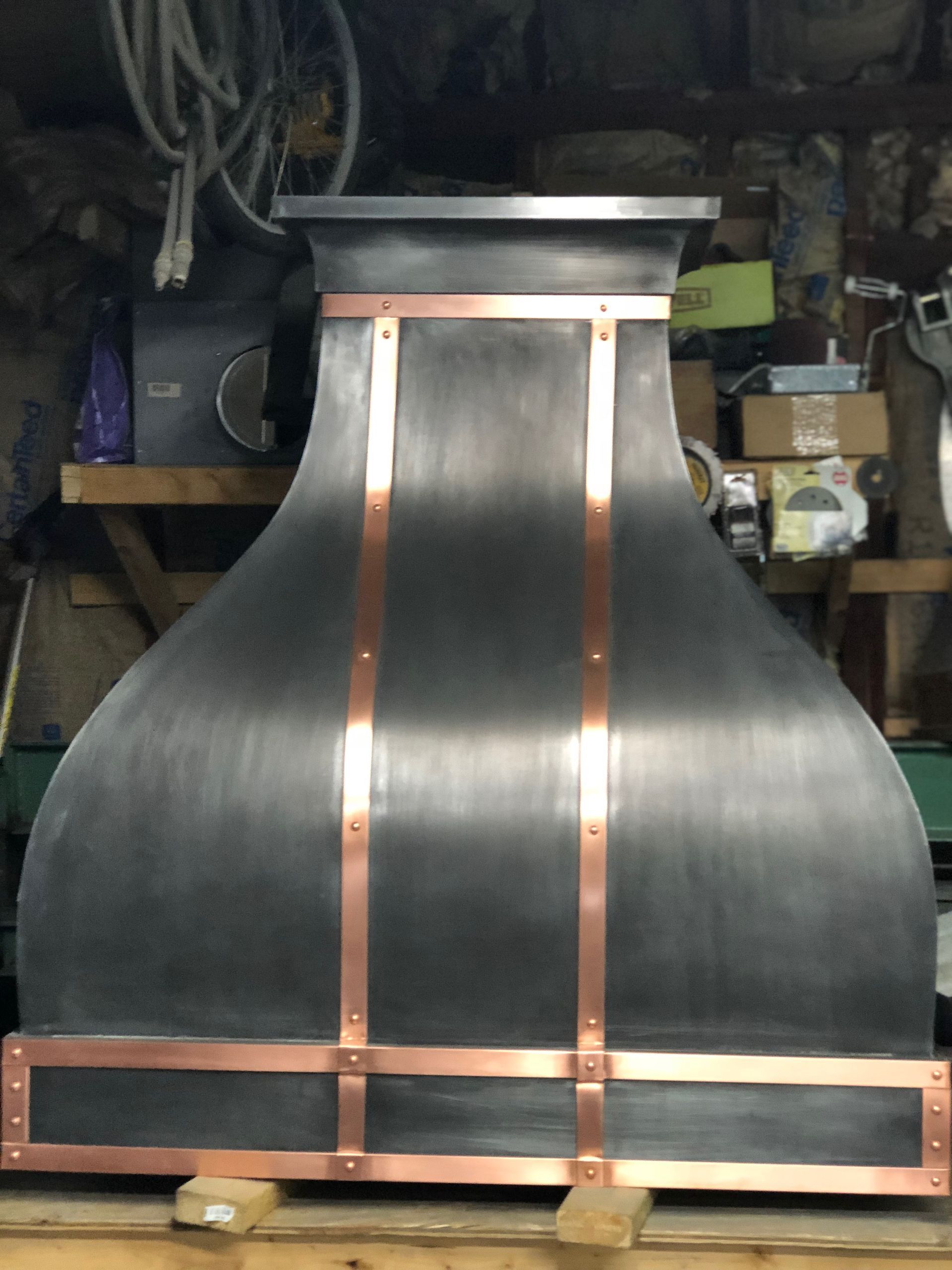 A black and copper hood is sitting on a wooden pallet.