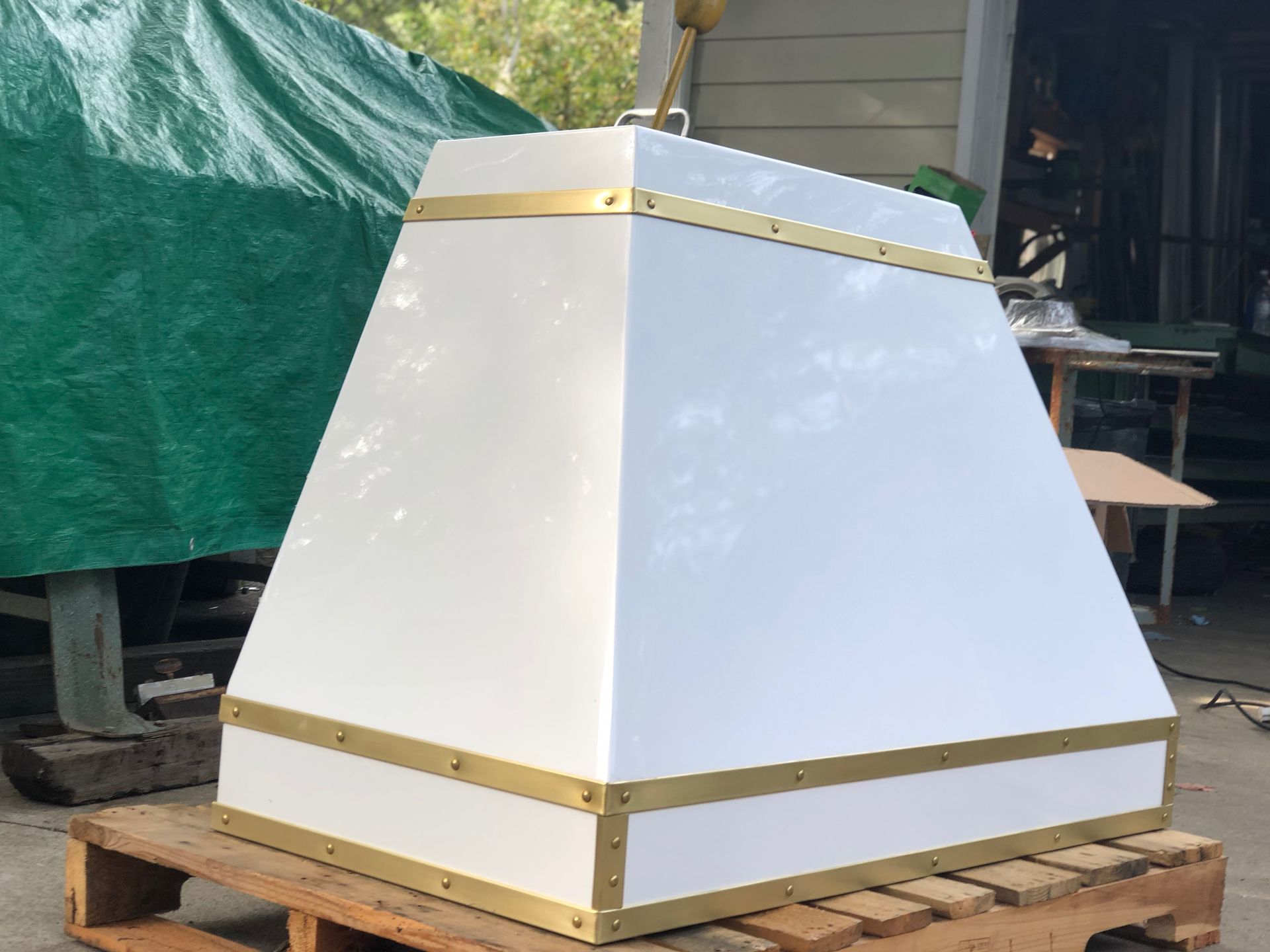 A white and gold hood is sitting on a wooden pallet.