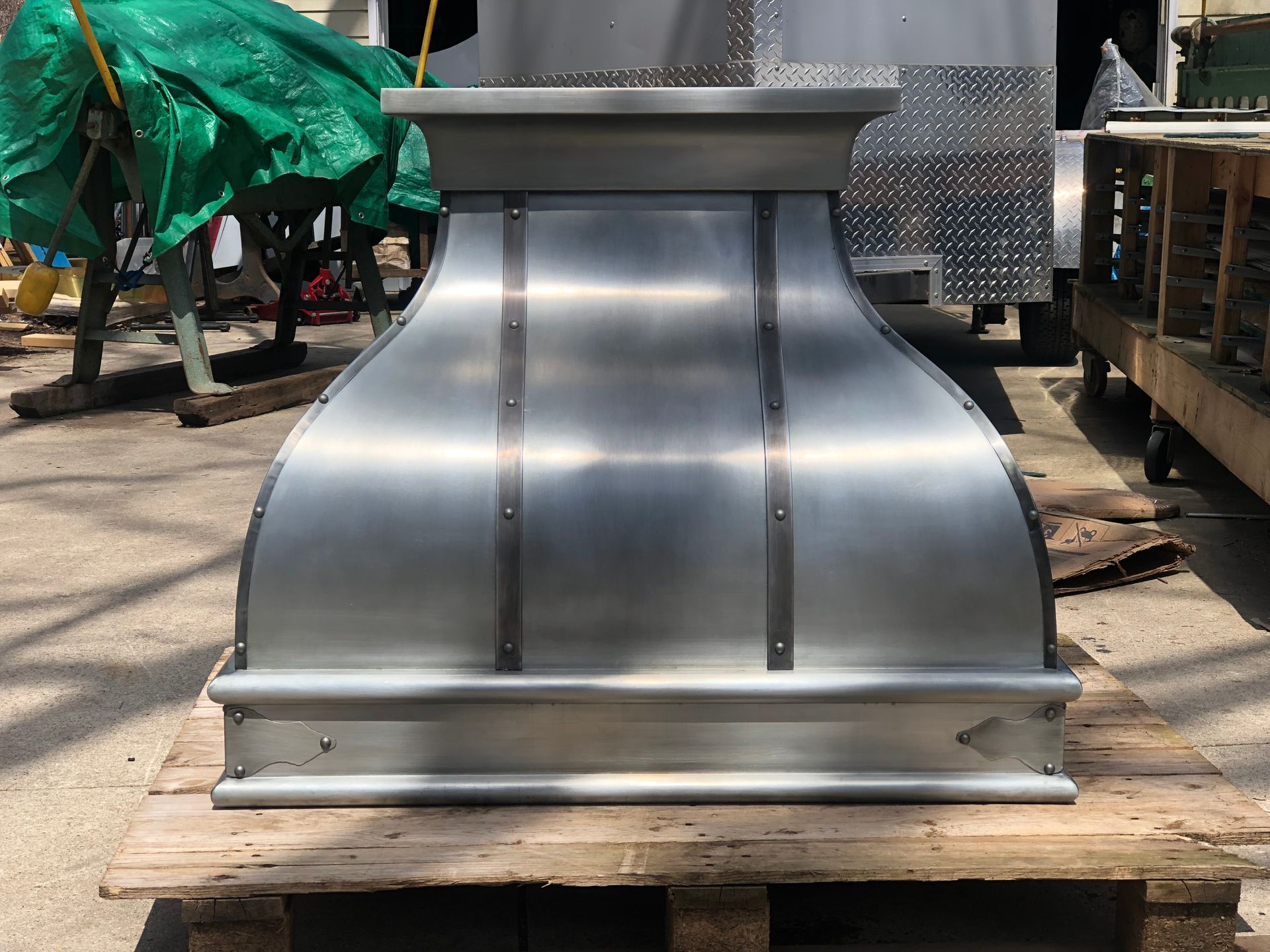 A stainless steel hood is sitting on a wooden pallet