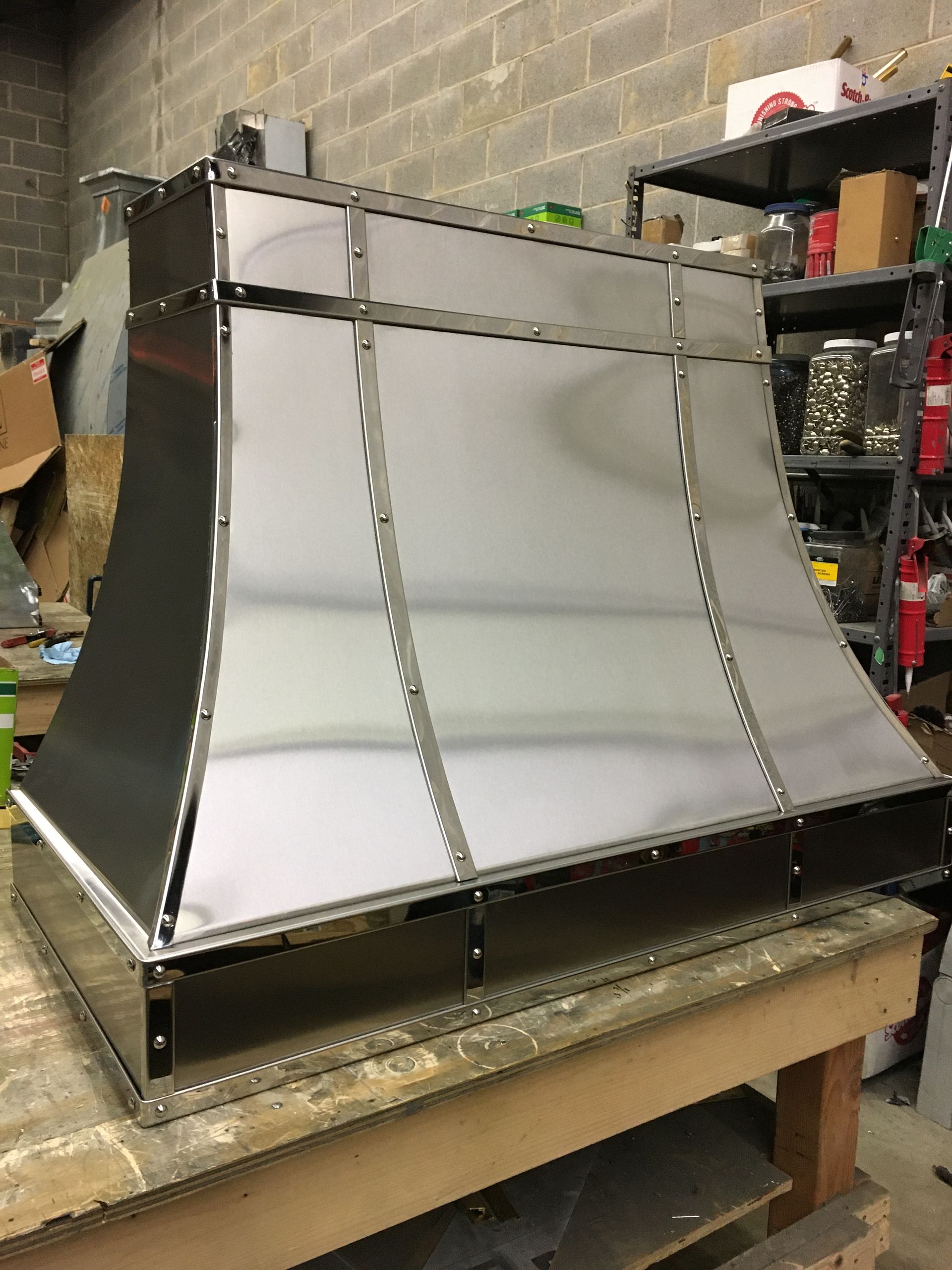 A stainless steel hood is sitting on top of a wooden table.