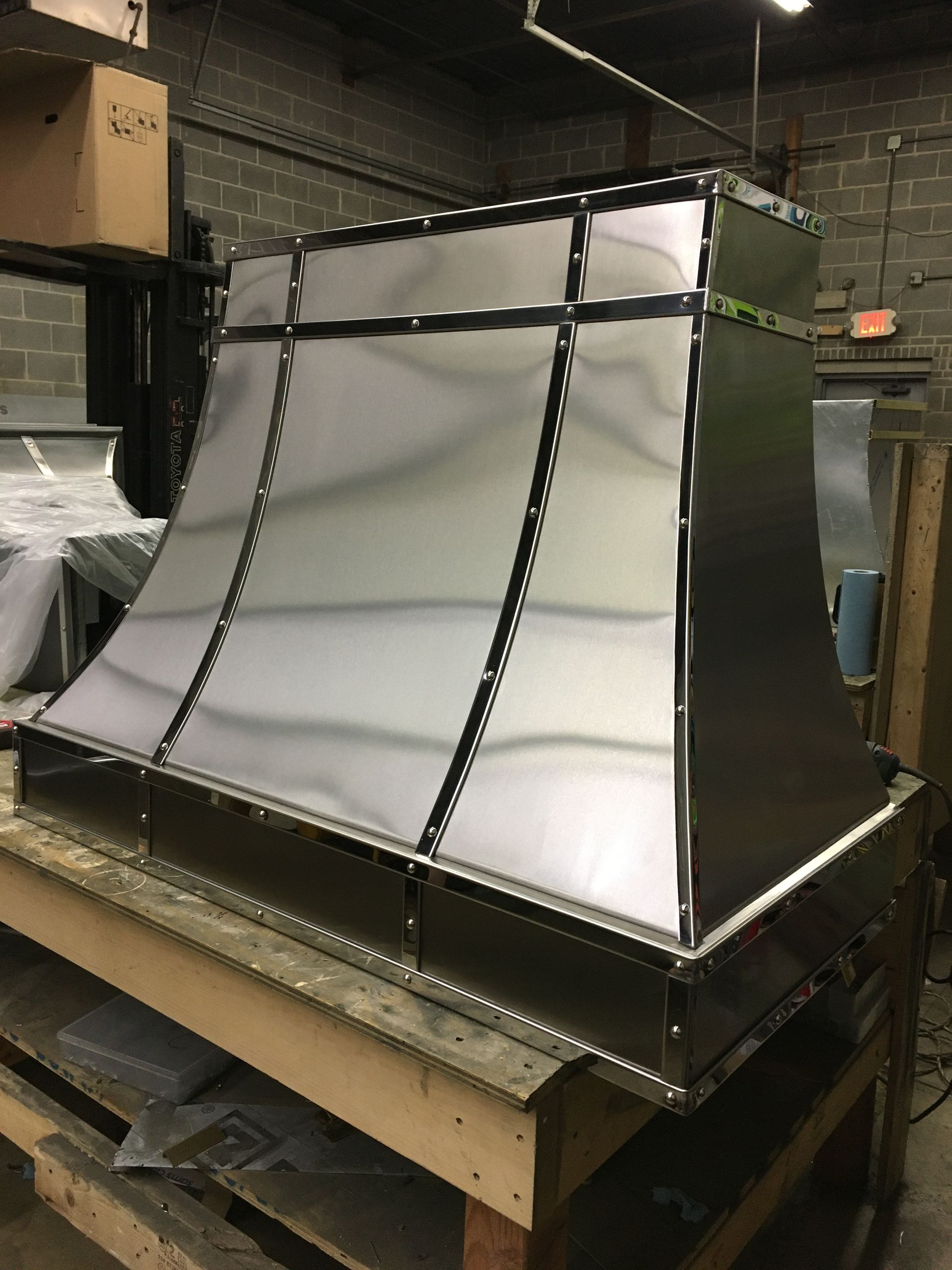 A stainless steel hood is sitting on top of a wooden table.