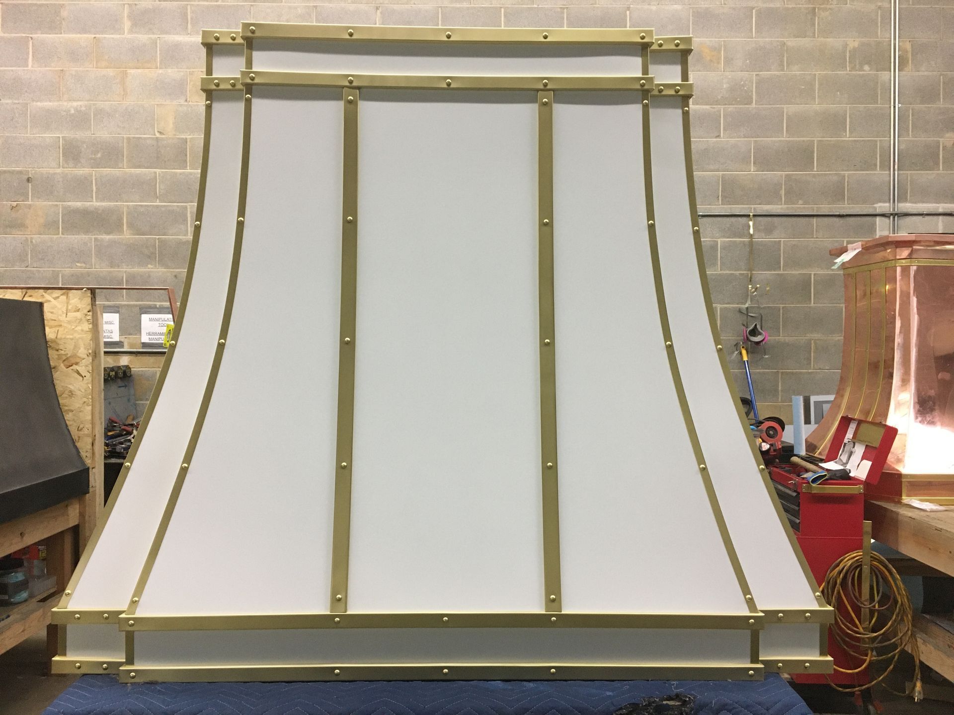 A white and gold lamp shade is sitting on a table in front of a brick wall.