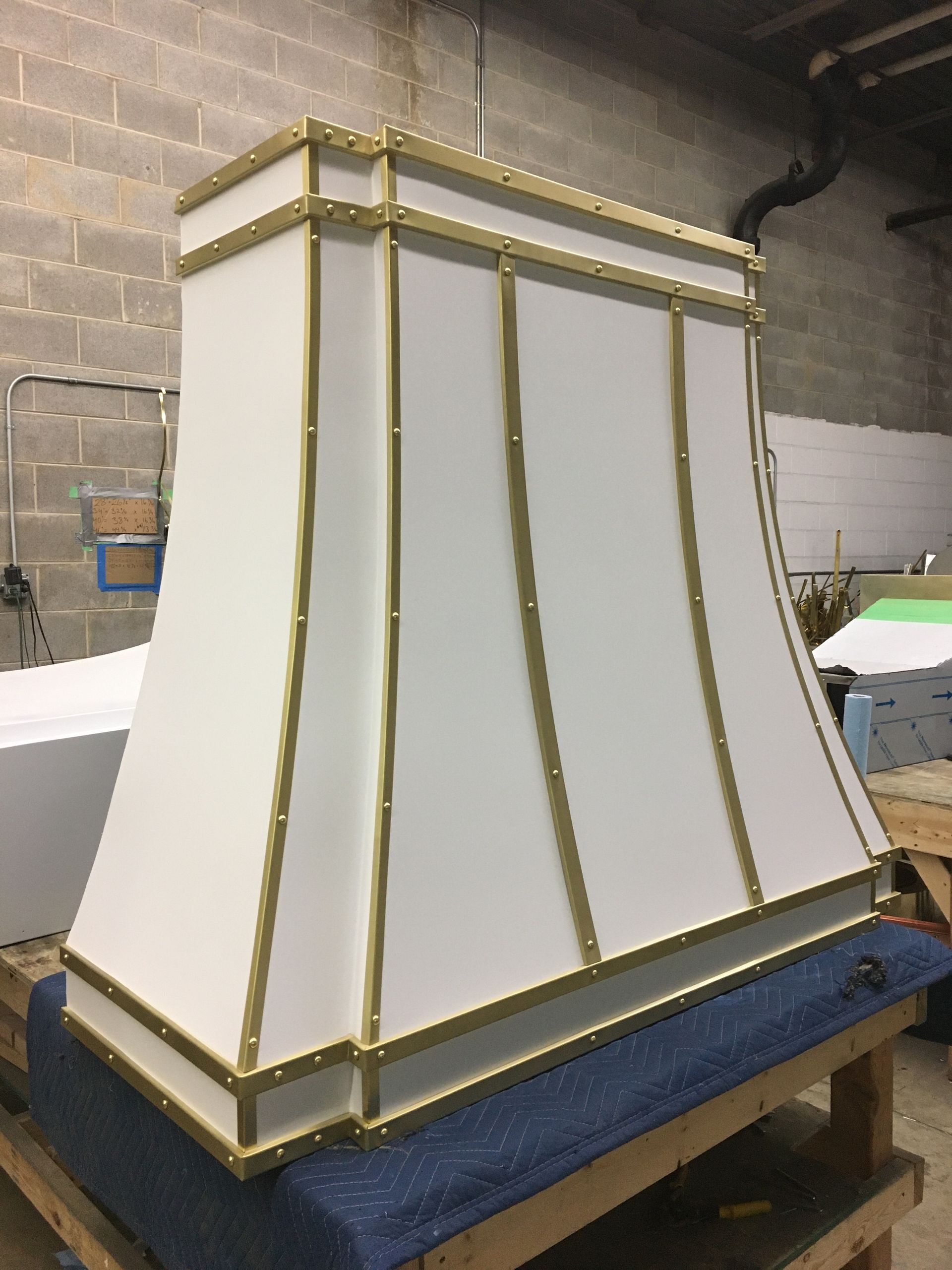 A white lamp shade with gold trim is sitting on a wooden table.
