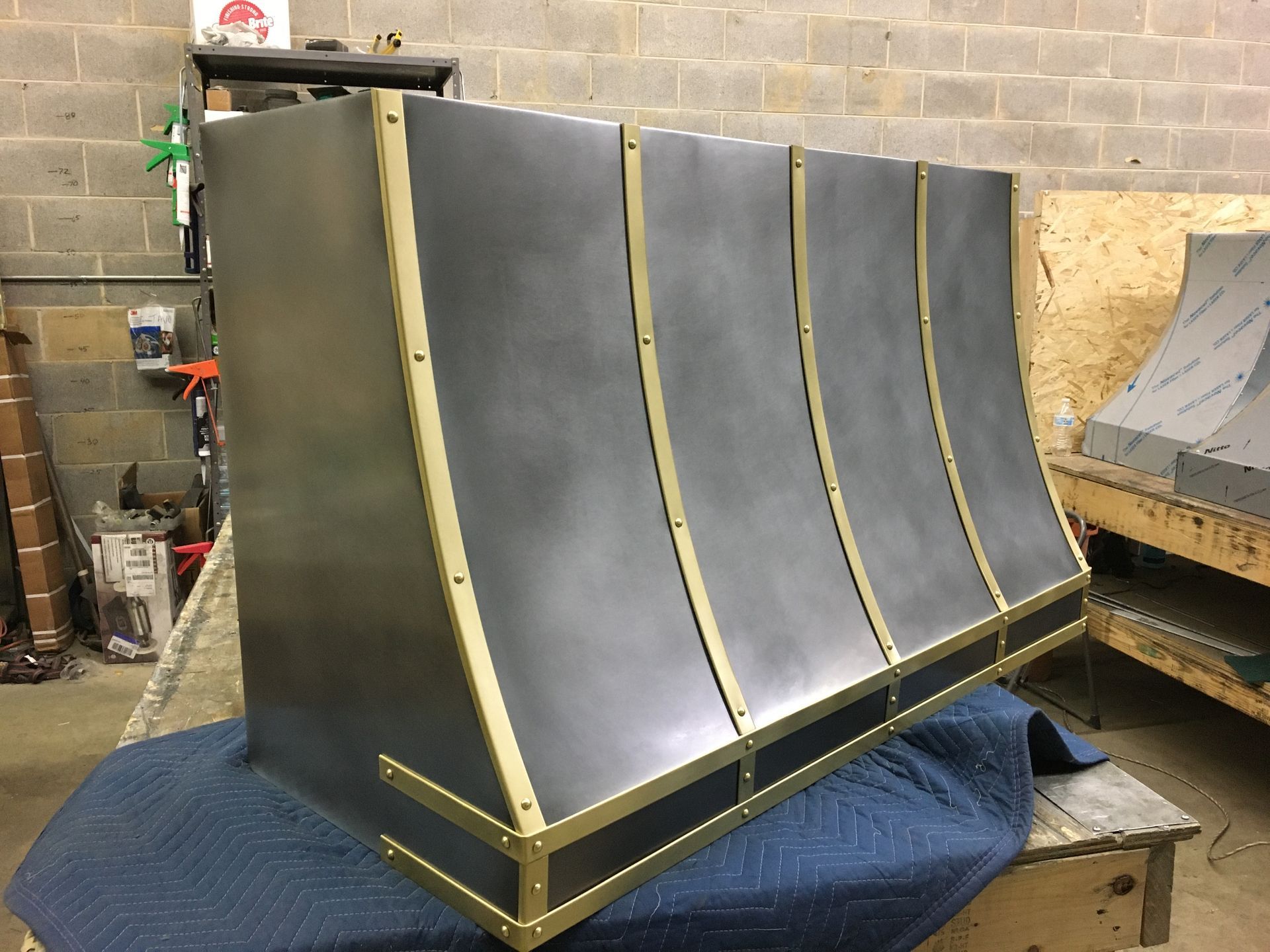 A stainless steel hood with brass trim is sitting on a table.
