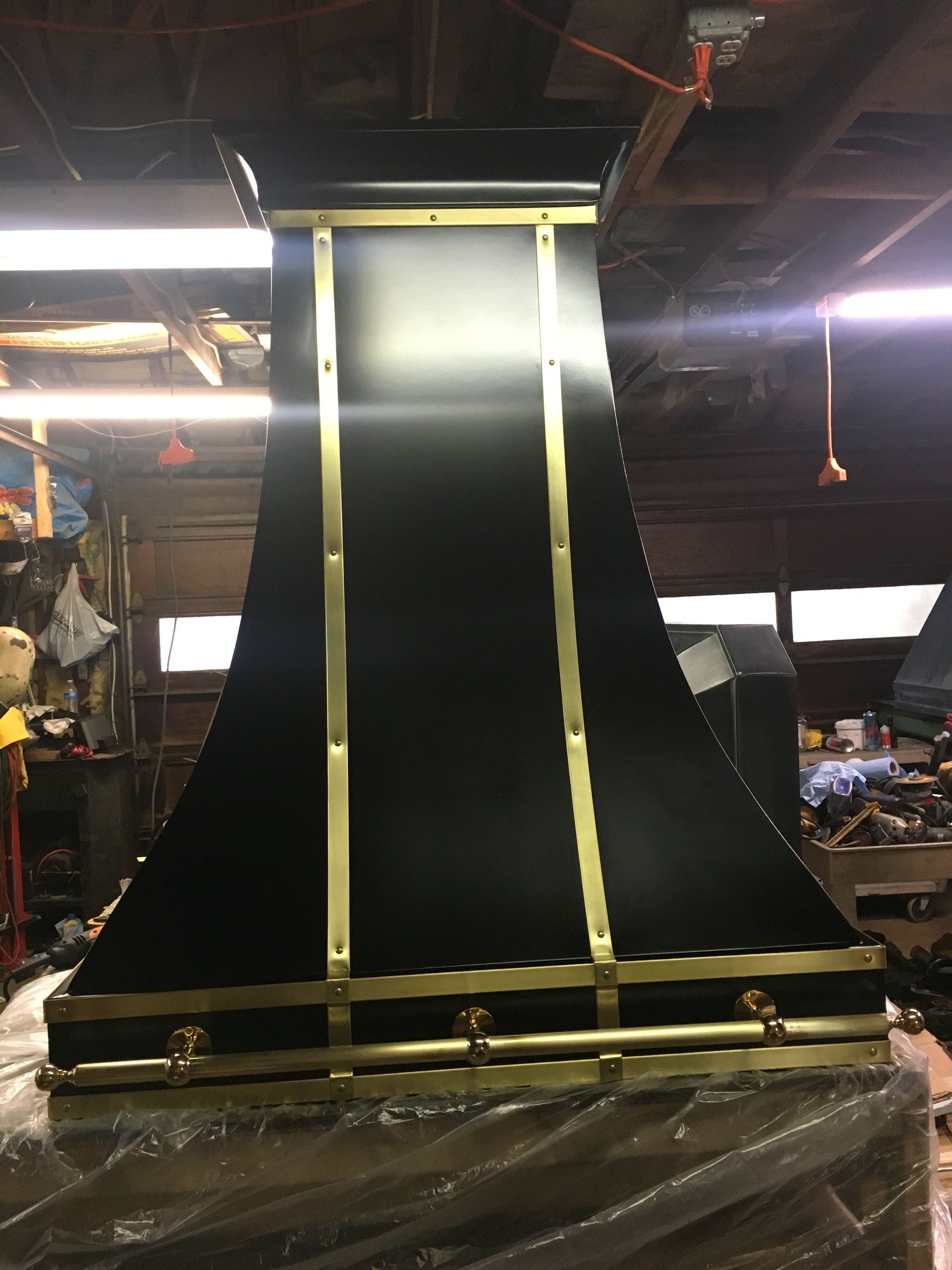 A black and gold hood is sitting in a garage.