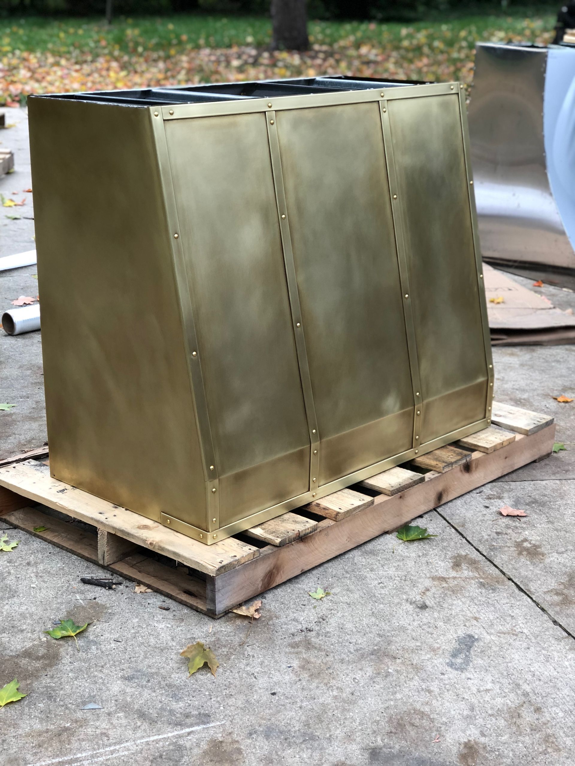 A brass box is sitting on top of a wooden pallet.