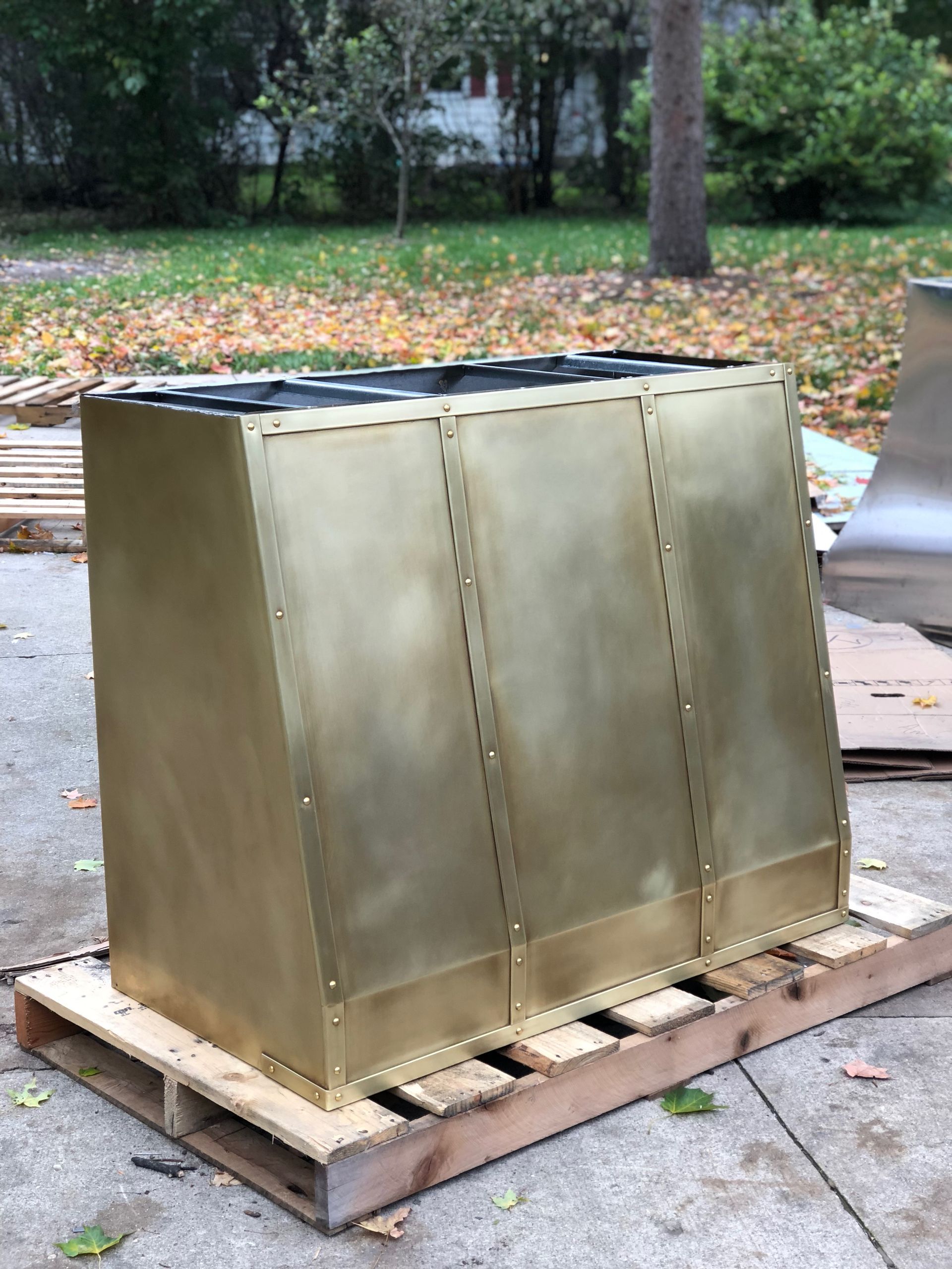A large brass box is sitting on top of a wooden pallet.