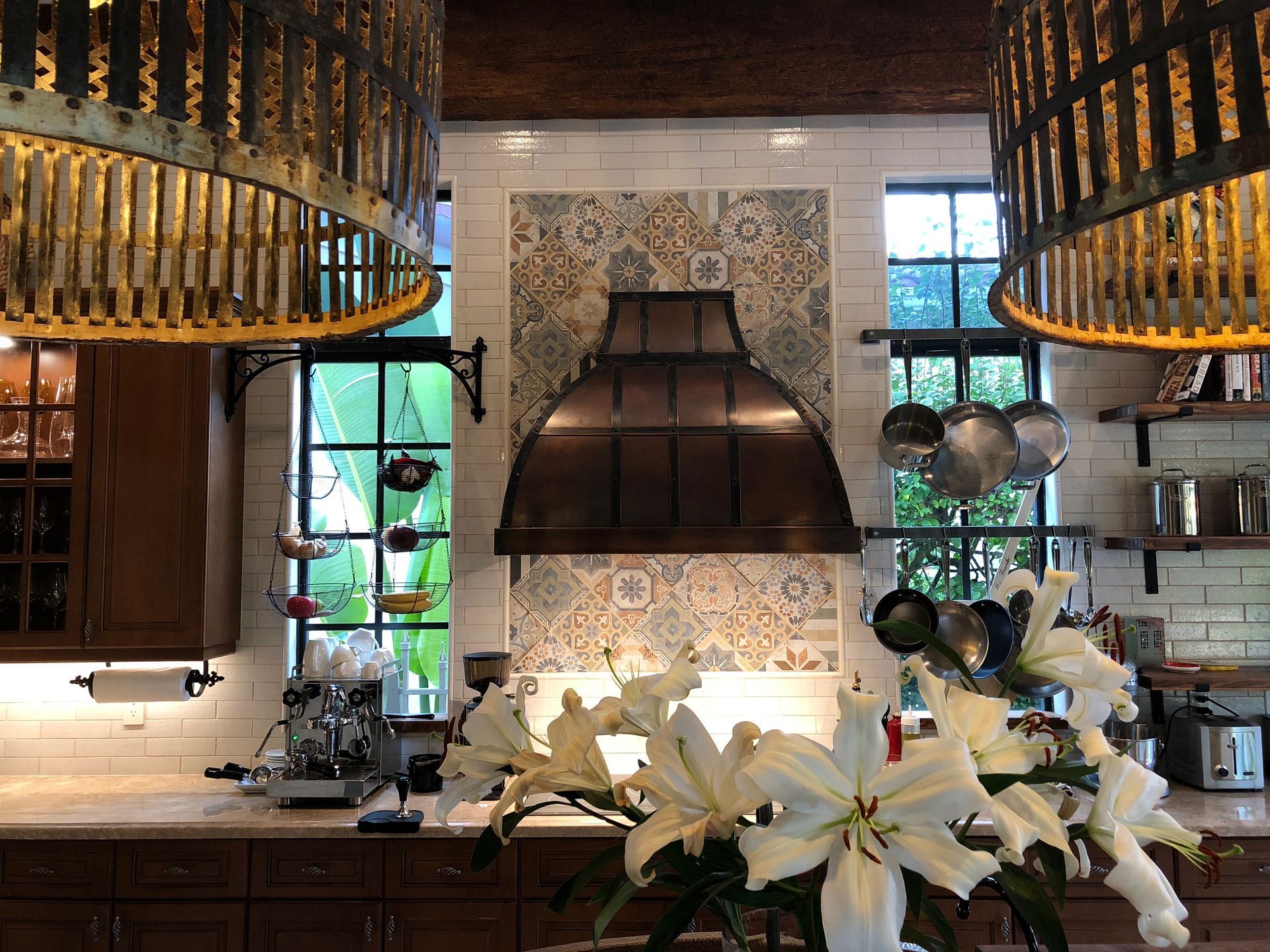 A kitchen with a copper hood and a vase of flowers