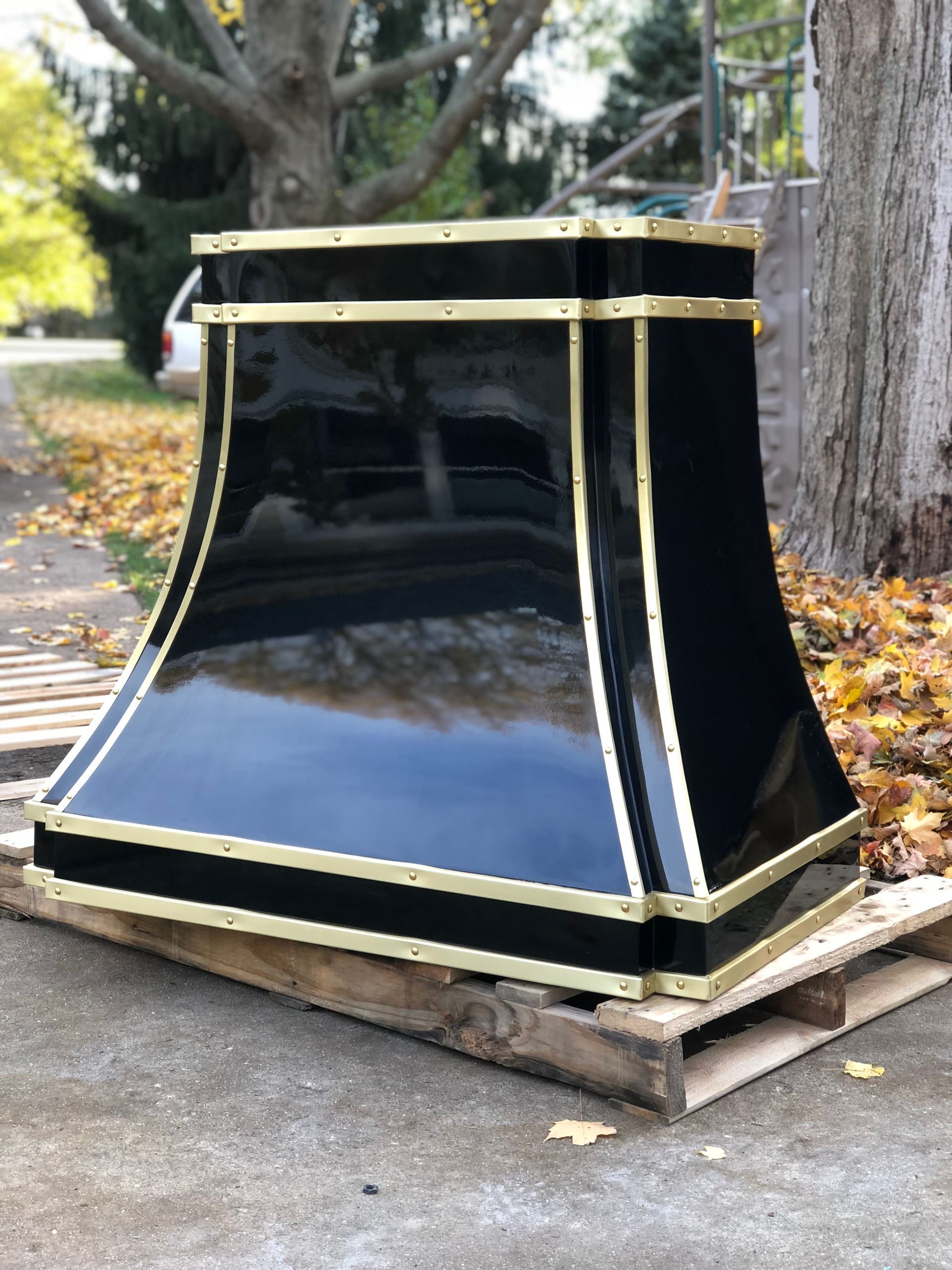 A black and gold hood is sitting on top of a wooden pallet.