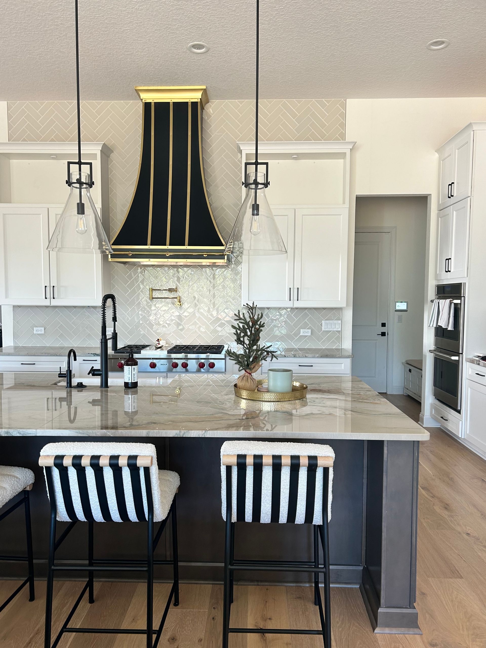 A kitchen with a black hood and striped bar stools