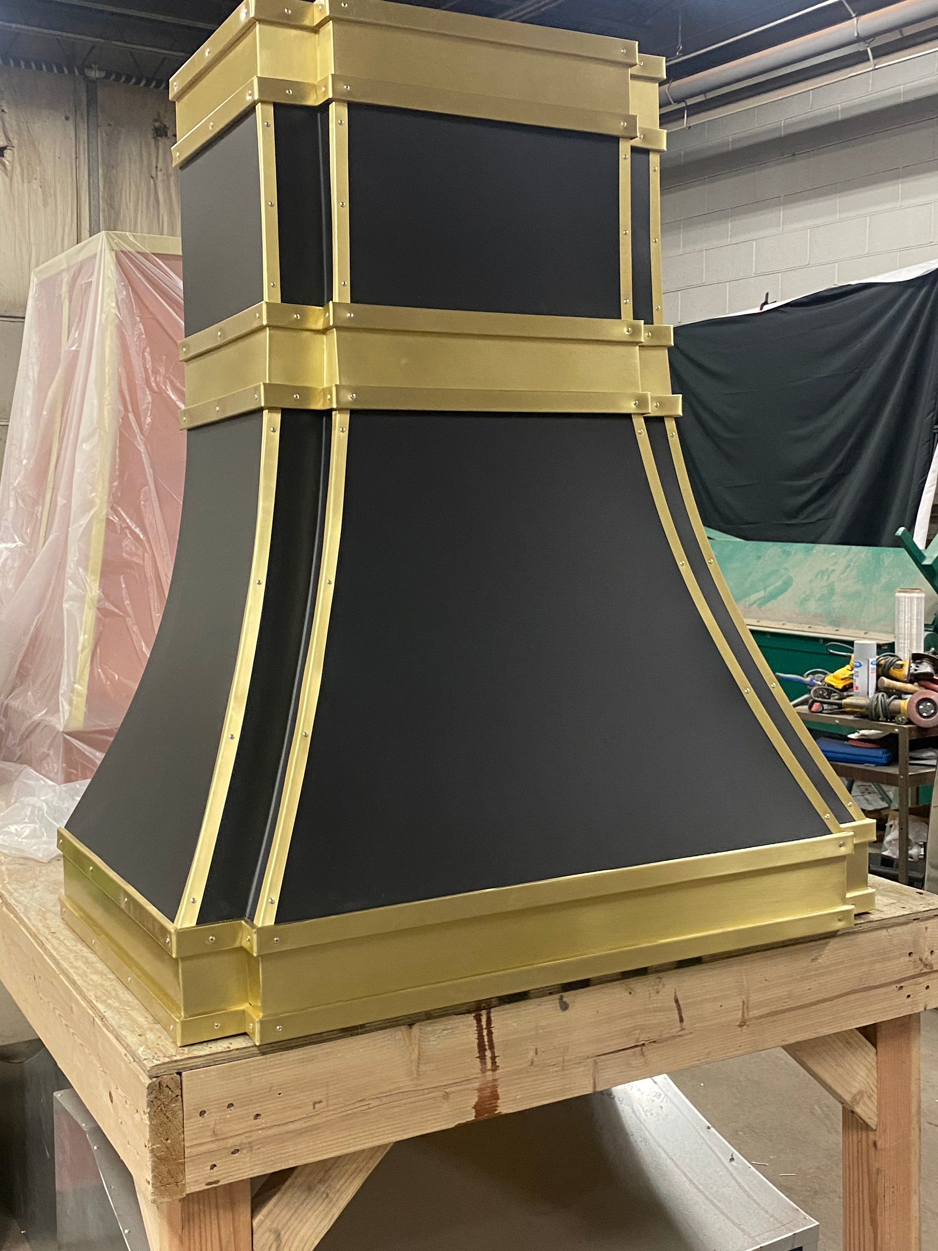 A black and gold hood is sitting on a wooden table.