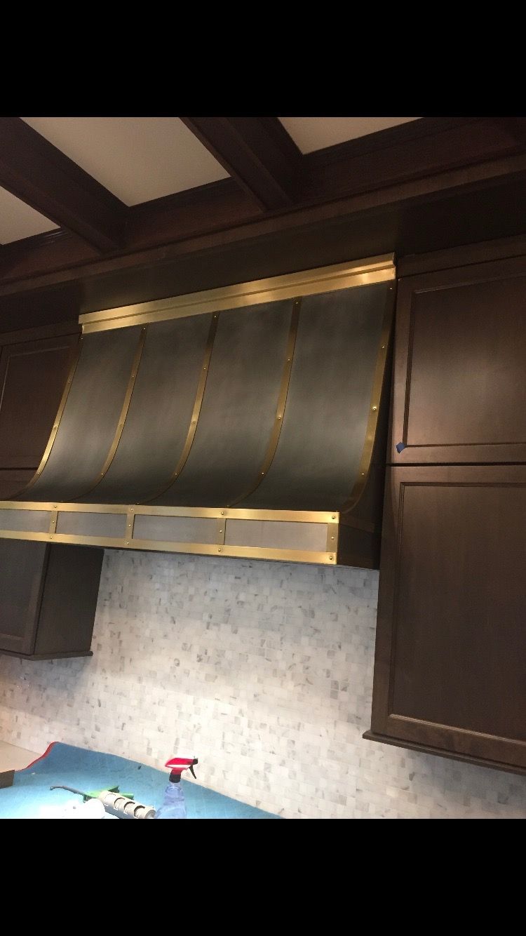 A kitchen with a copper hood and wooden cabinets.