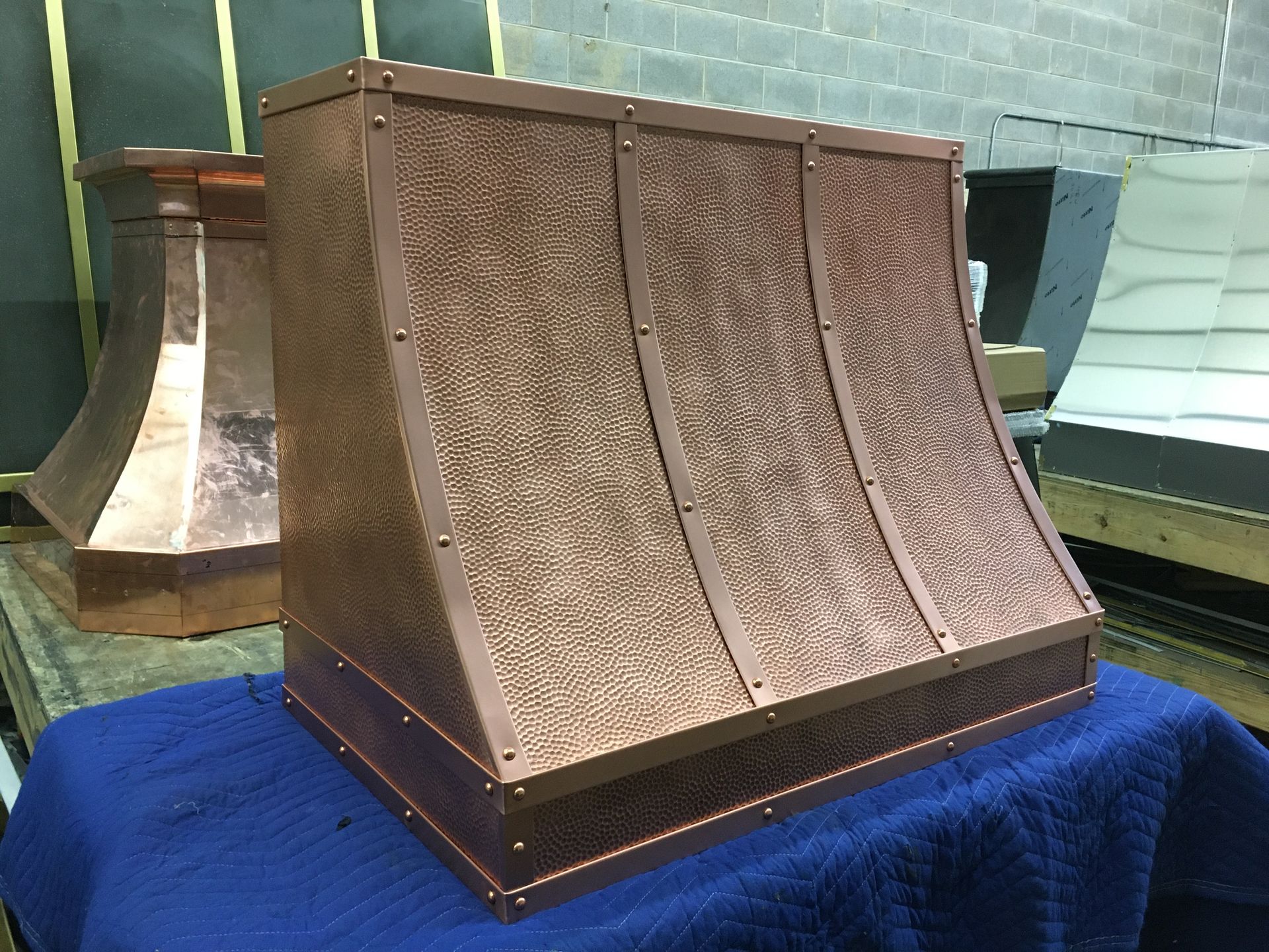 A copper hood is sitting on top of a blue towel on a table.