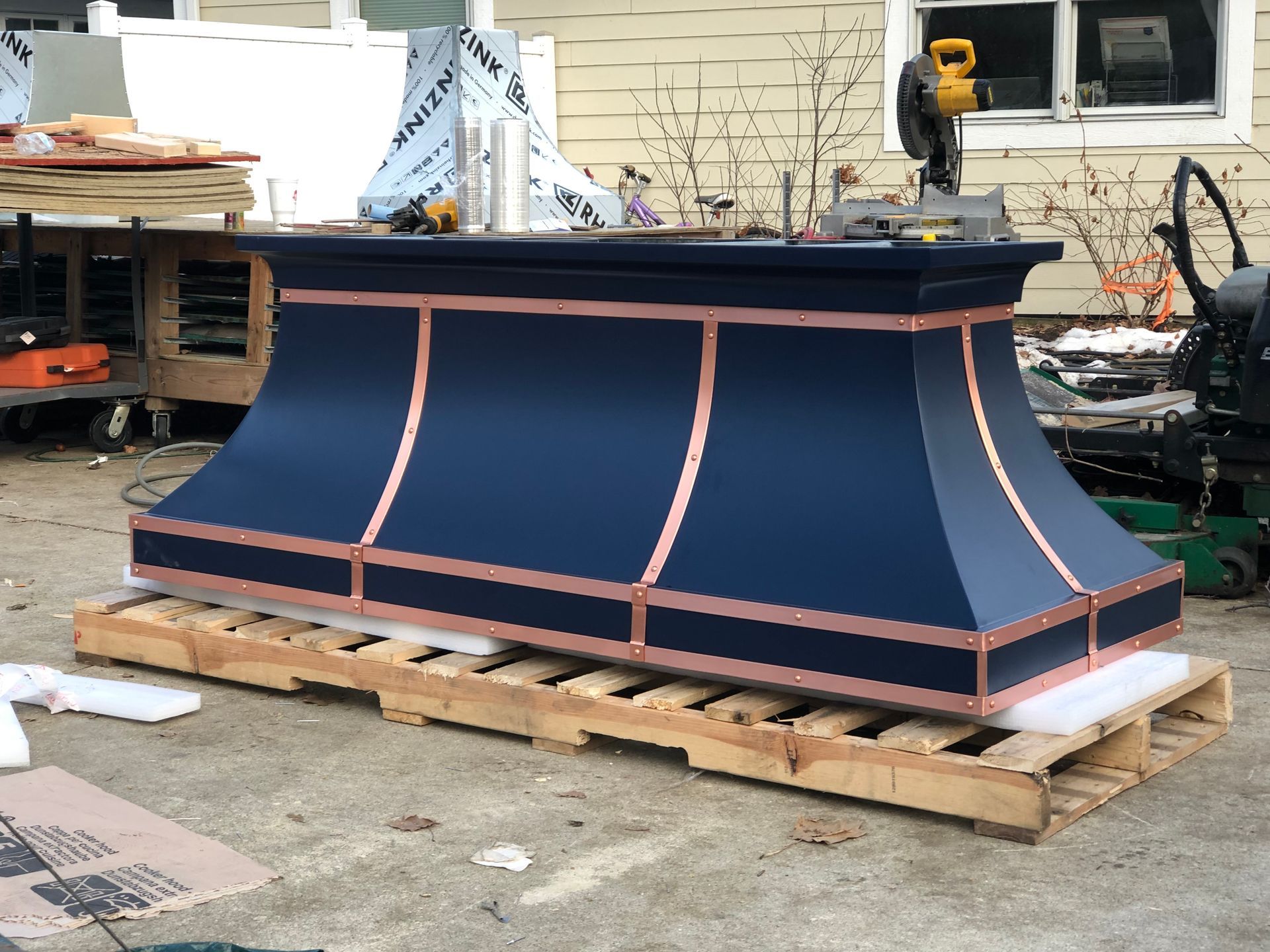 A blue and copper hood is sitting on a wooden pallet.