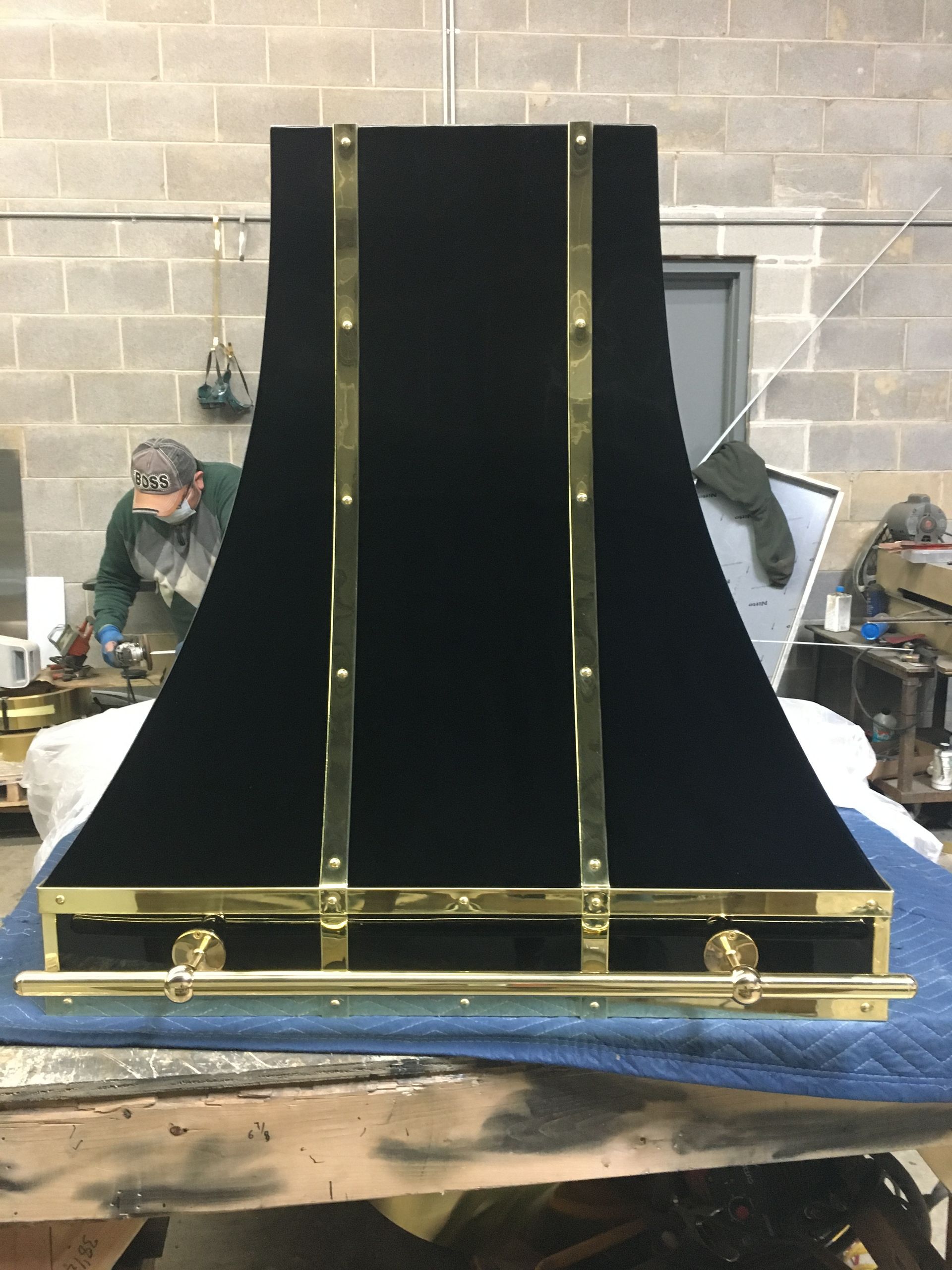 A black hood with brass trim sits on a table