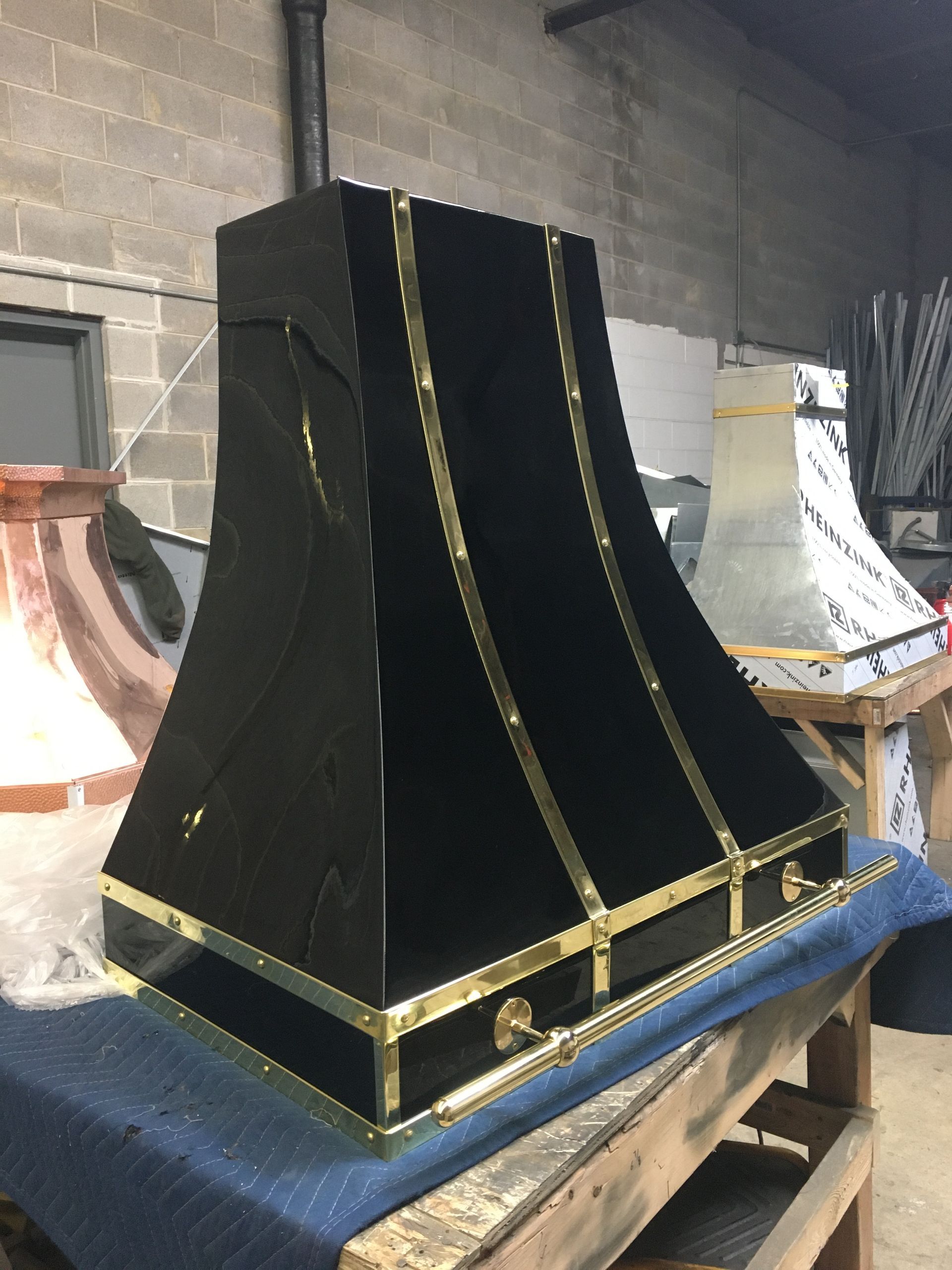 A black and gold hood is sitting on top of a wooden table.