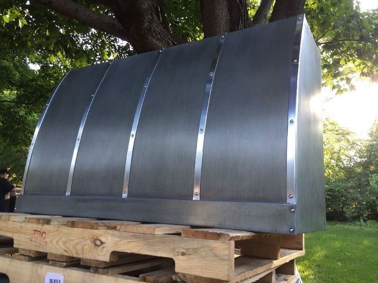 A stainless steel hood is sitting on top of a wooden pallet