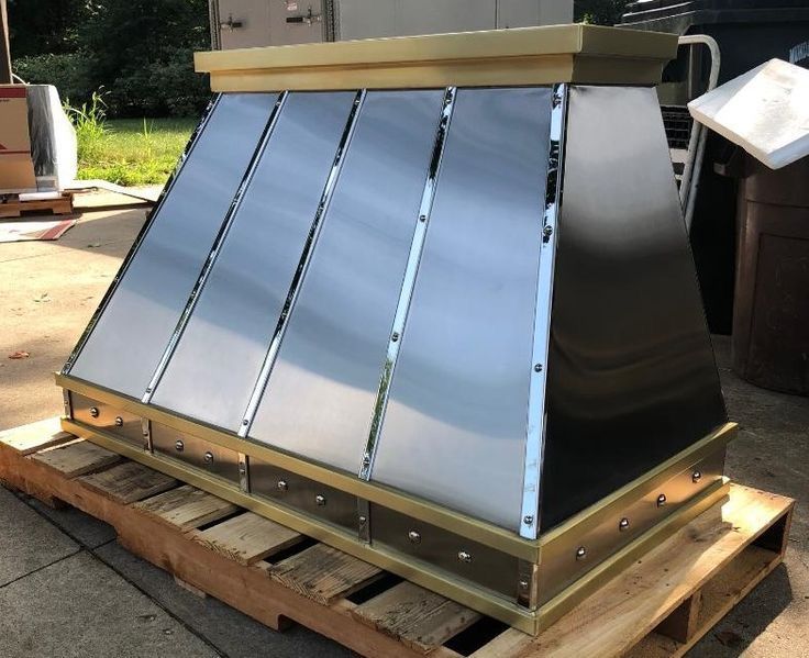 A stainless steel hood is sitting on a wooden pallet