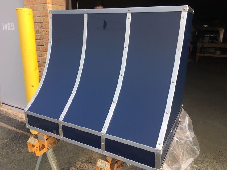 A blue awning is sitting on a wooden stand in front of a brick building.