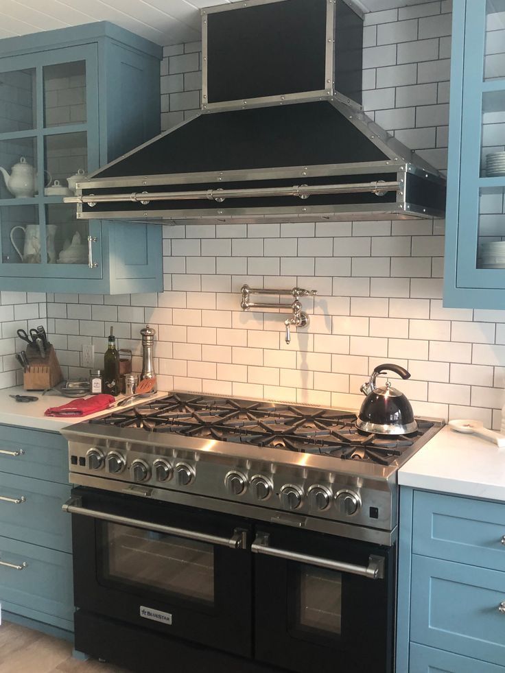 A kitchen with a black stove top oven and blue cabinets
