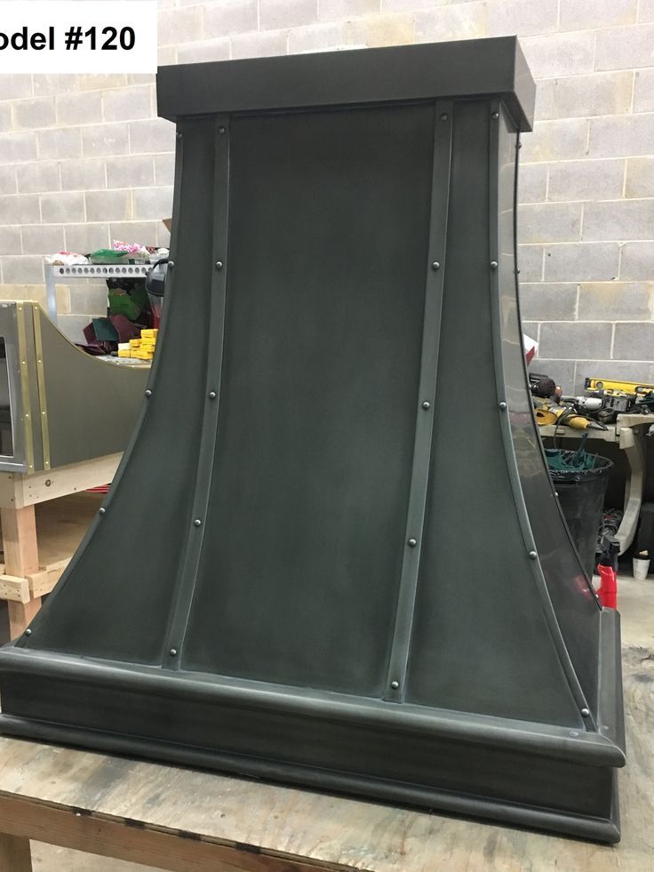 A black metal hood is sitting on top of a wooden table.