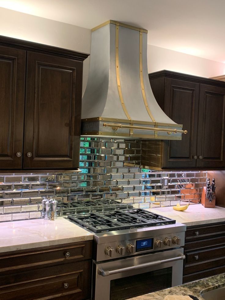 A kitchen with a stove and a hood above it.