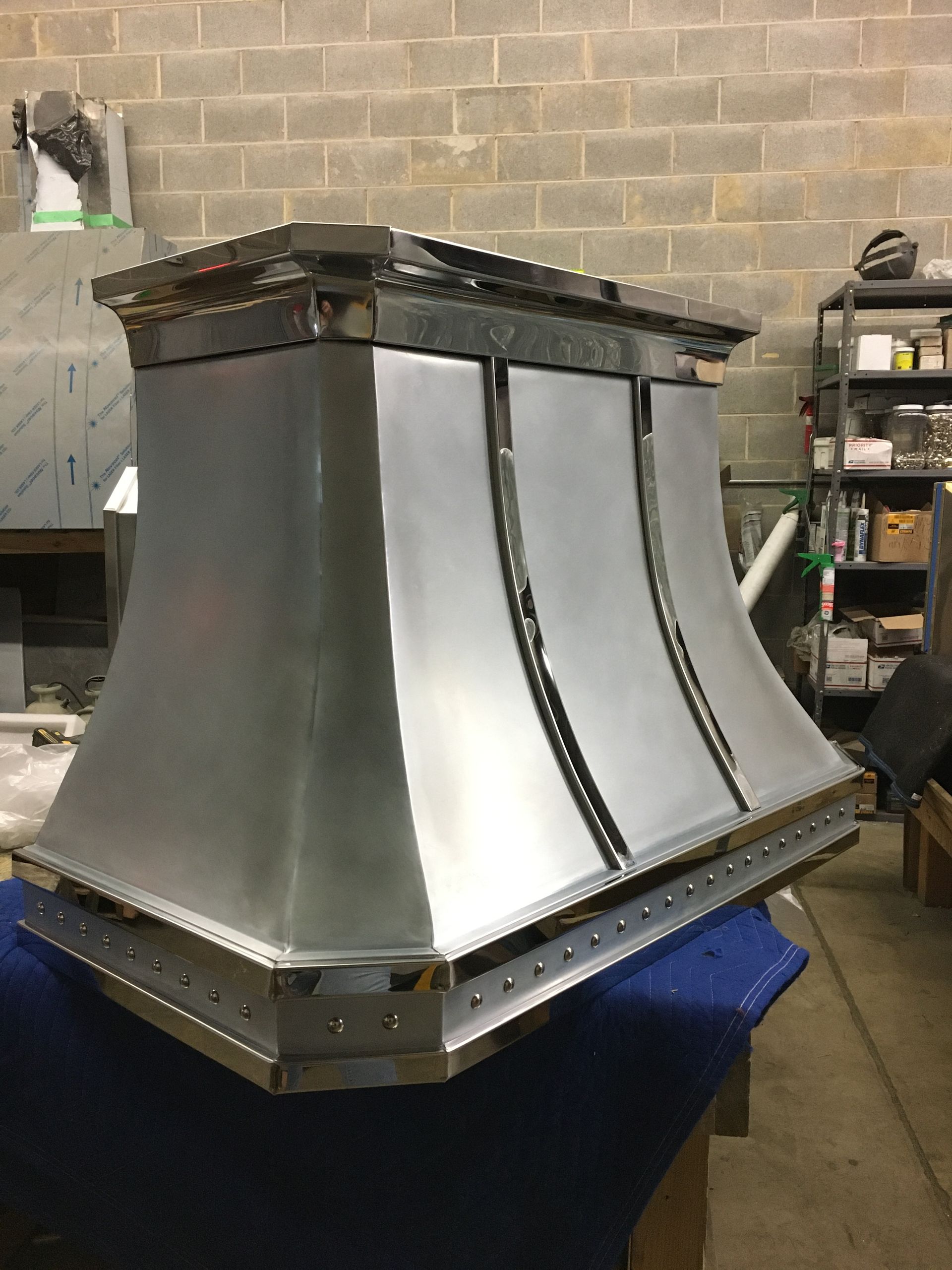 A stainless steel hood is sitting on a table in a warehouse.