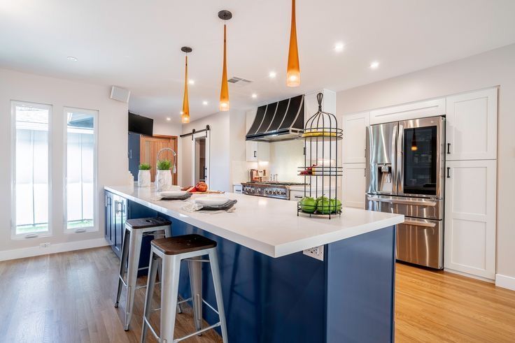 A kitchen with blue cabinets , white counter tops , stainless steel appliances and a large island.