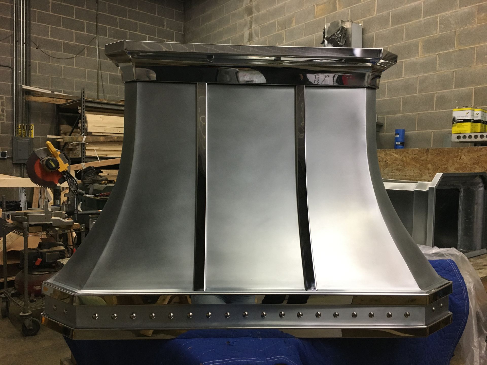 A stainless steel hood is sitting on top of a blue table.